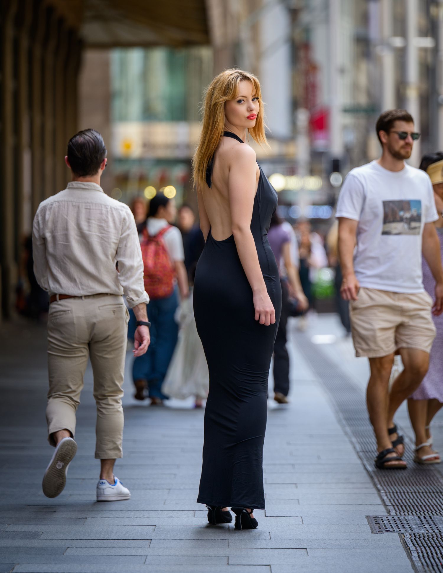 Woman in black dress walking down urban sidewalk shown in artistic sequence of motion blur shots.
