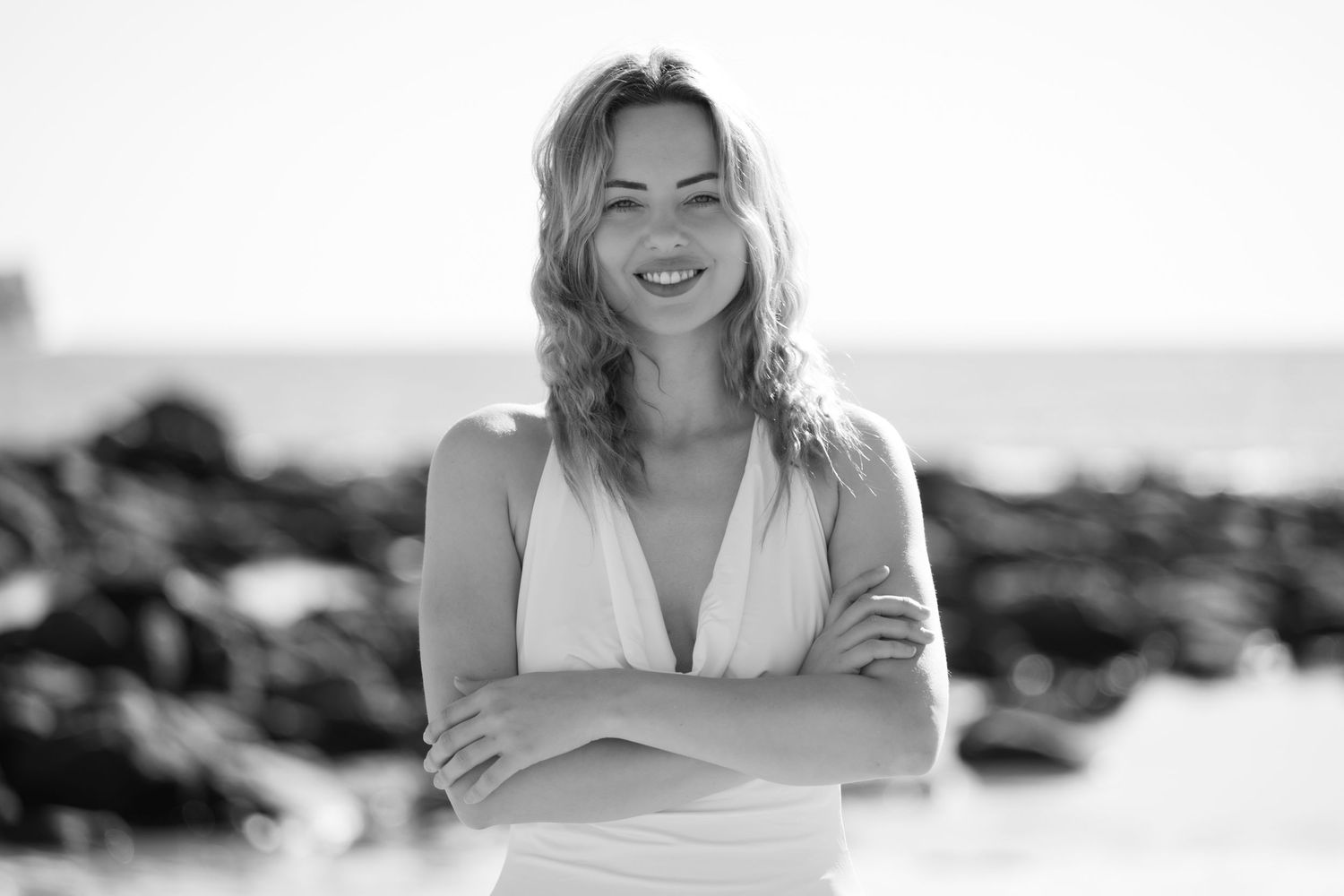 A series of black and white beach portraits showing joyful expressions and casual poses.