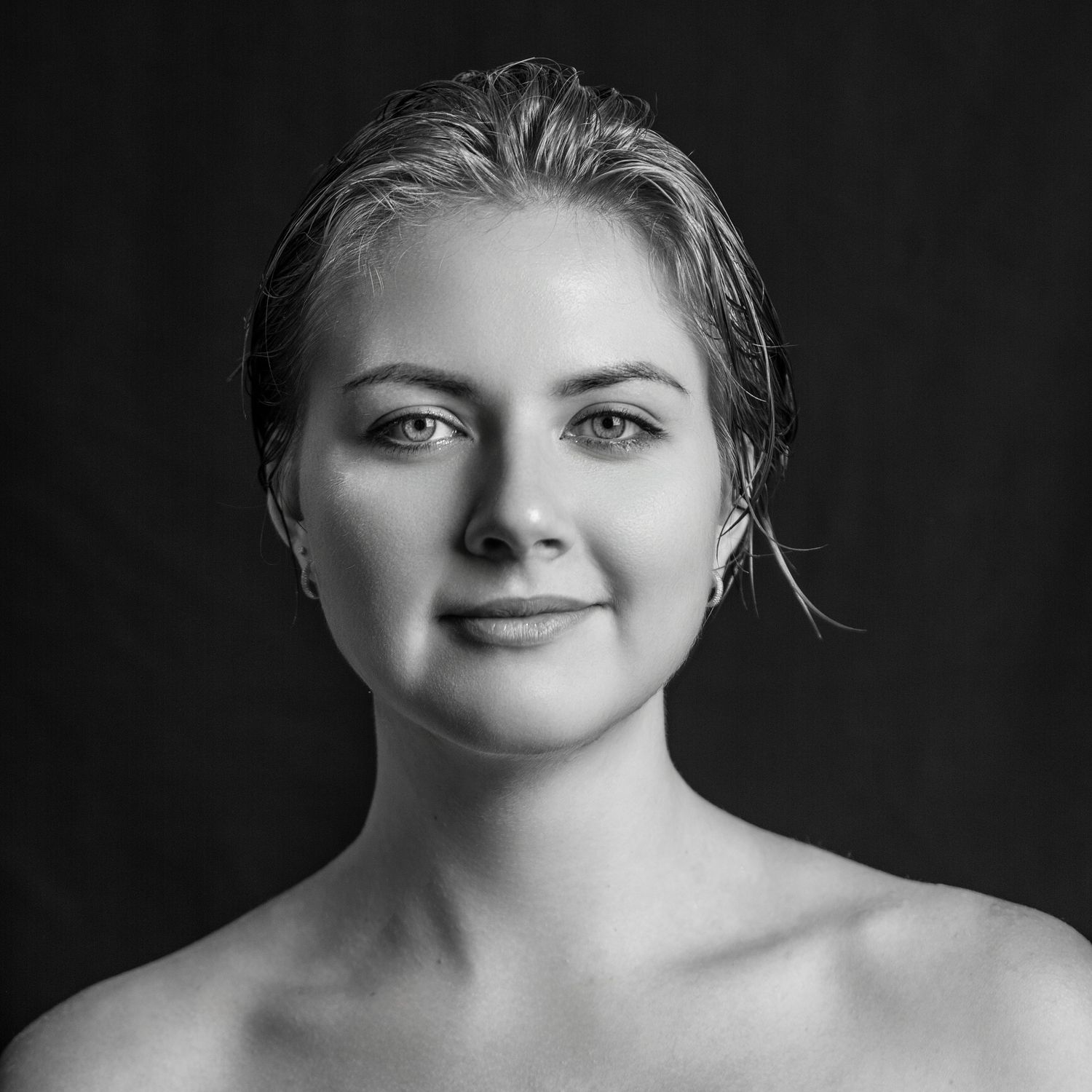 Dramatic black and white portrait series with dark background and soft lighting.