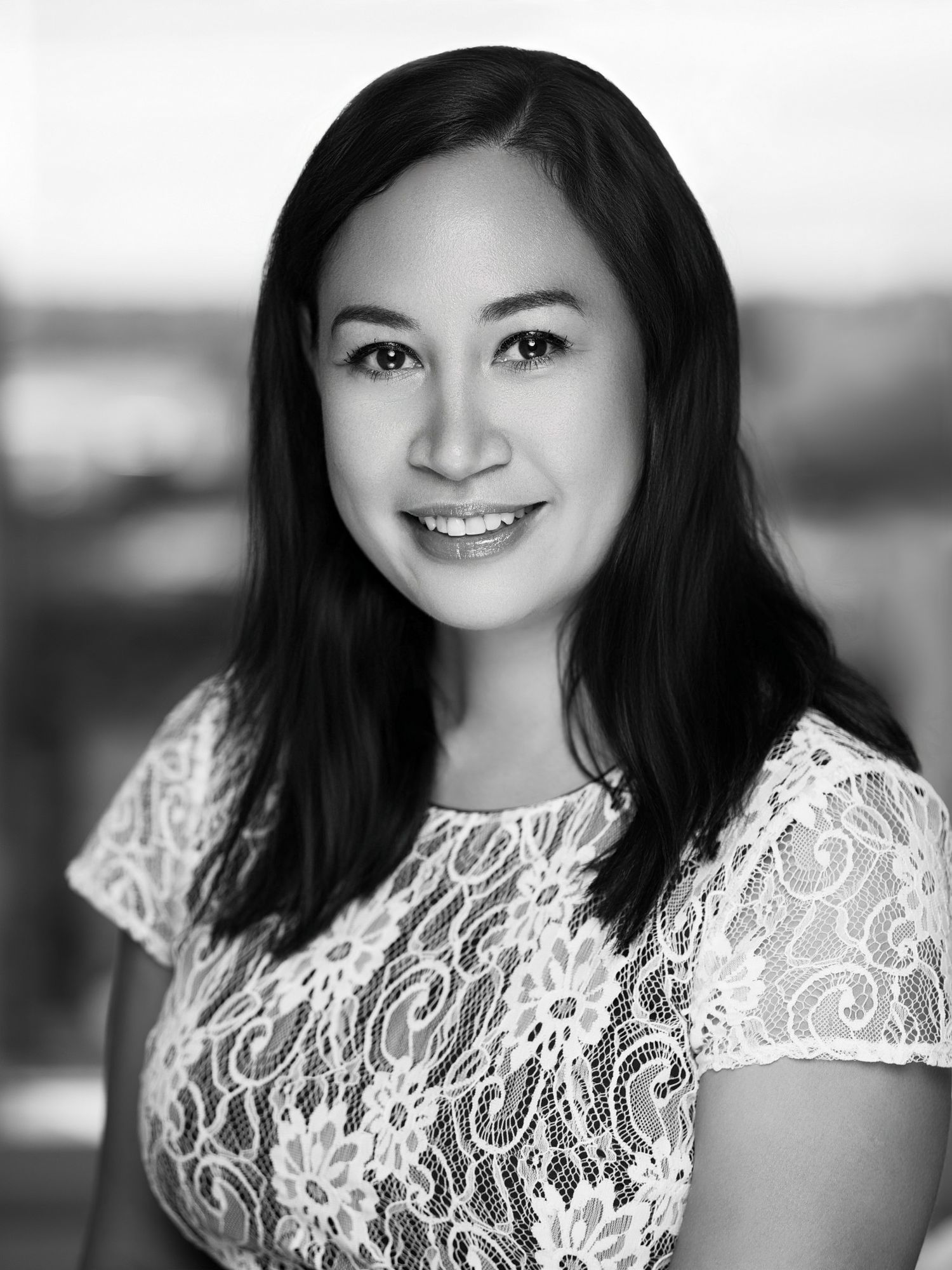 Portrait of person in white lace dress smiling at camera against blurred background.