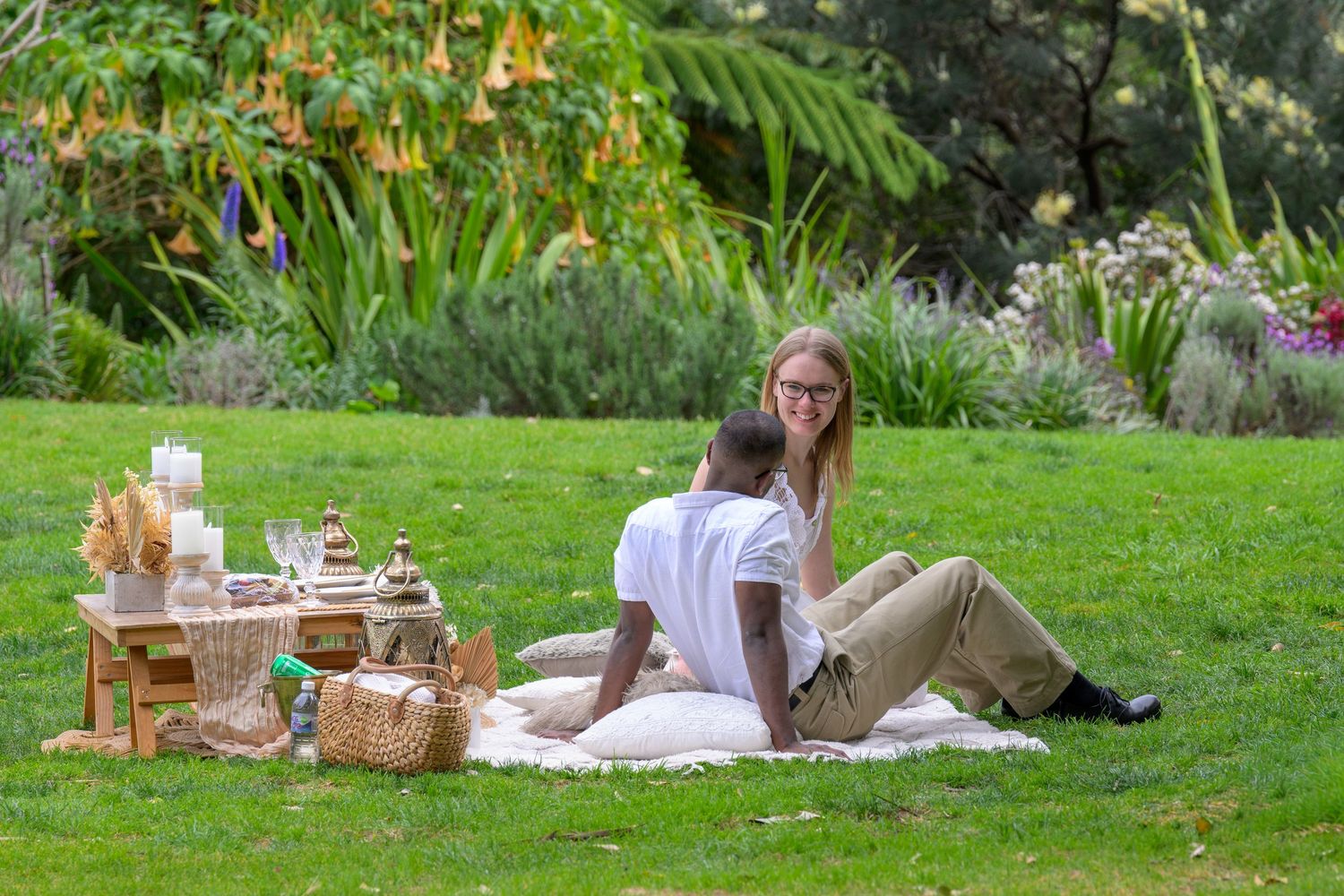People enjoying a summer picnic on lush green grass with blankets and food.
