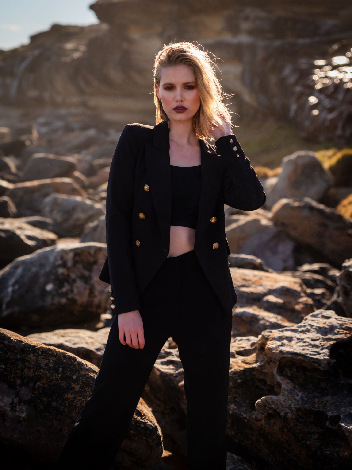 Fashion portrait series on rocky terrain at sunset featuring model in black outfit.