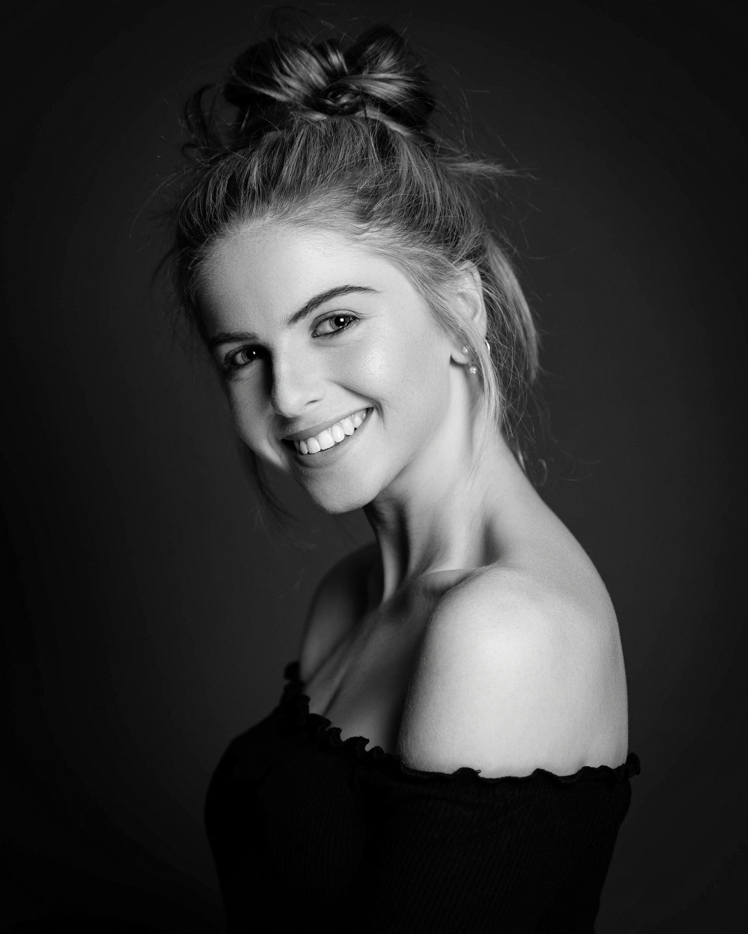 Dramatic black and white portrait series with soft lighting against dark background.