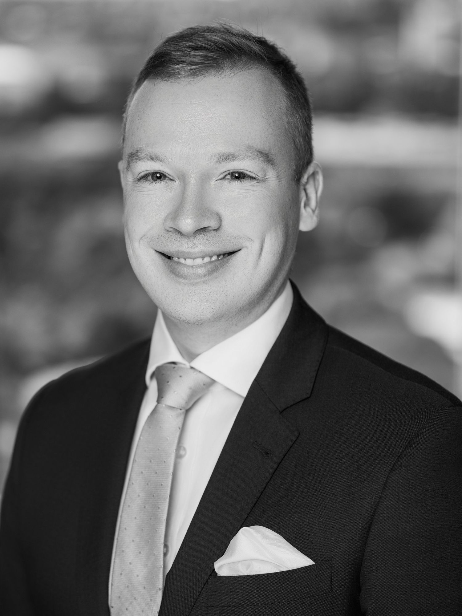 Black and white corporate portrait of person in business attire with white tie.
