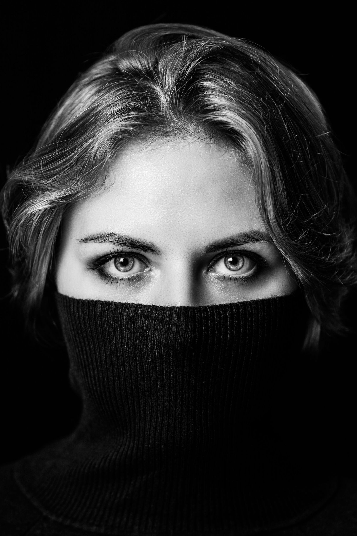 Dramatic black and white series showing eyes peeking above a dark turtleneck sweater.