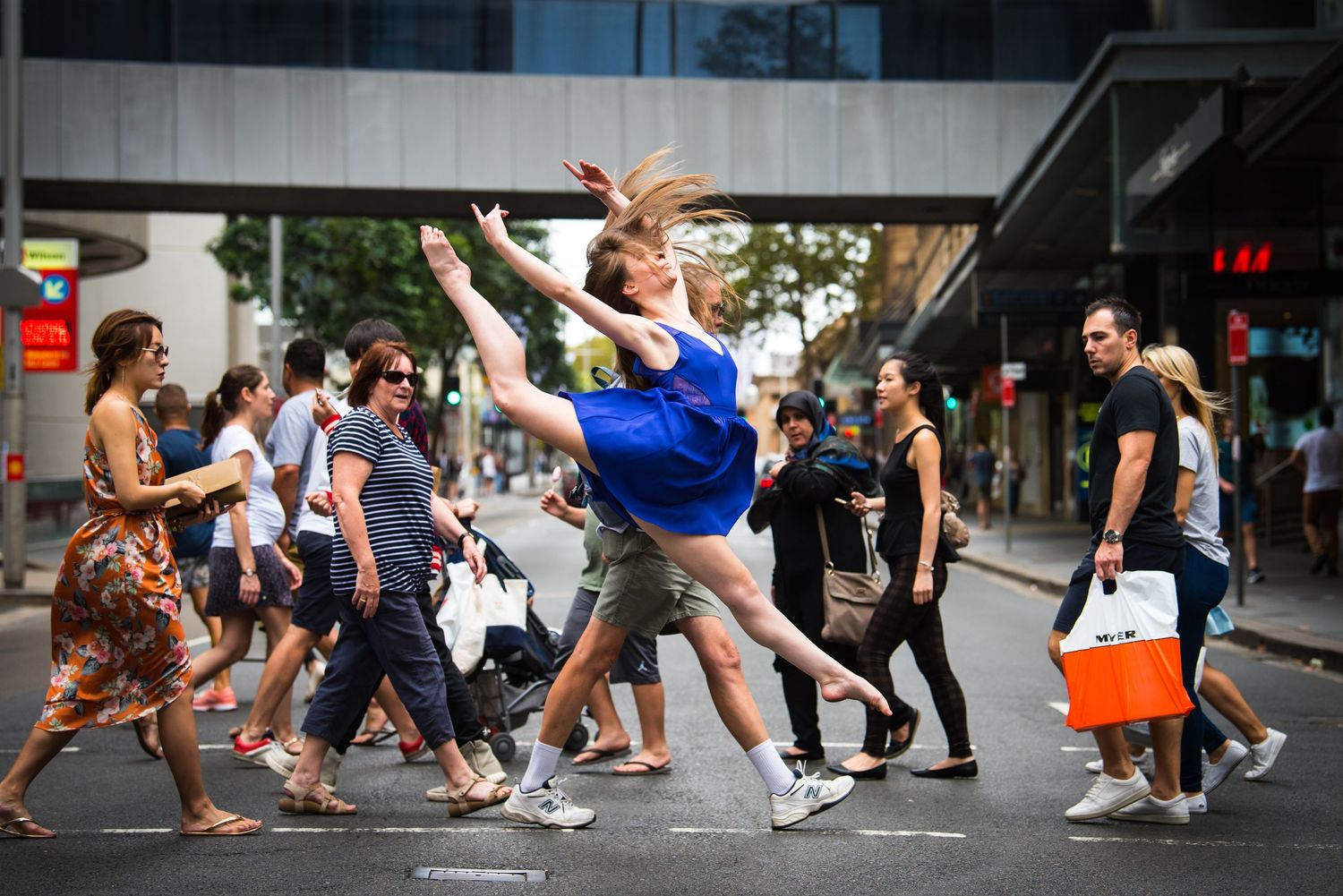 Urban dance scene with multiple people performing coordinated dance moves on a sidewalk.