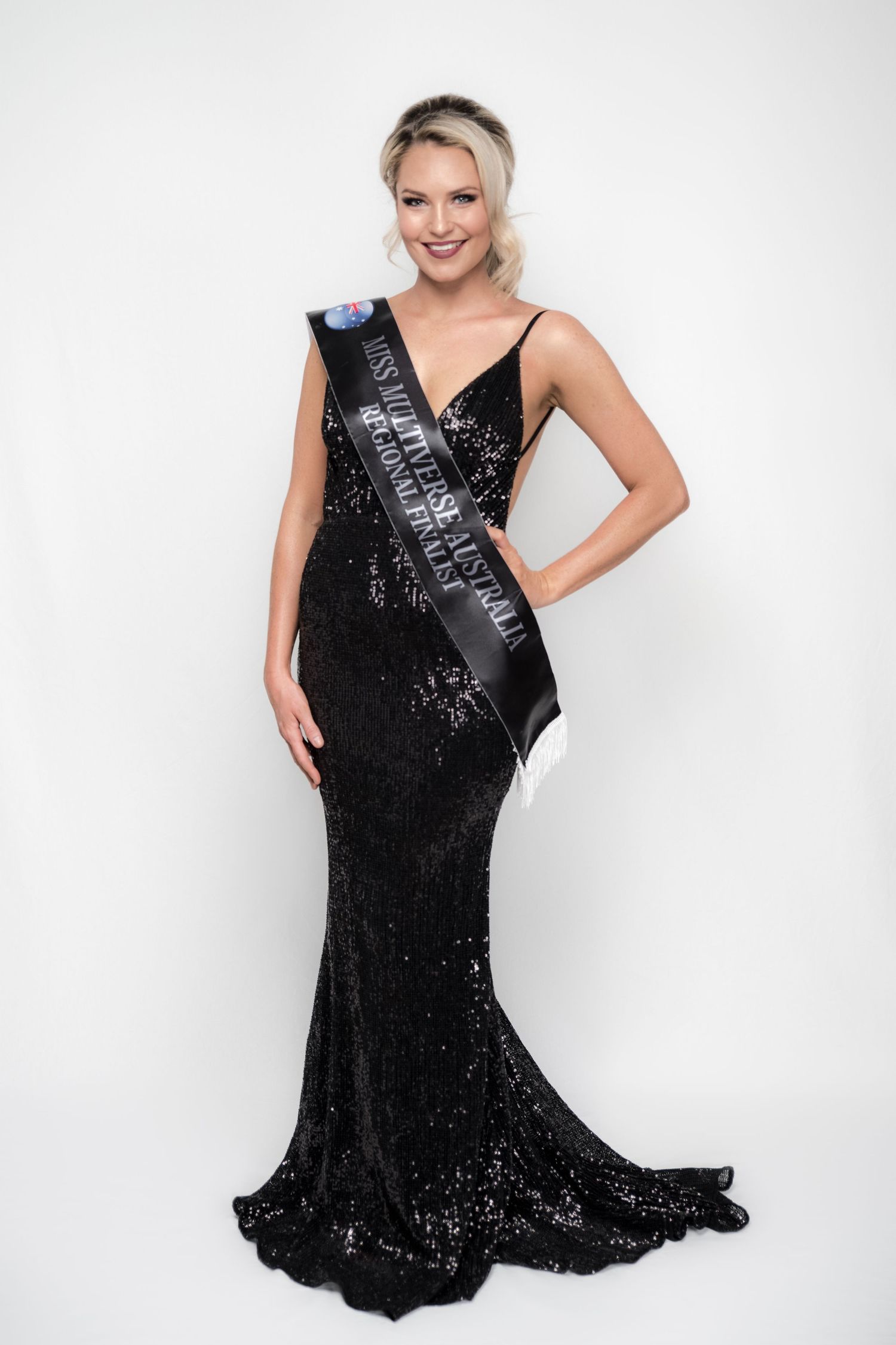 Glamorous poses in sparkling black evening gown against white backdrop.