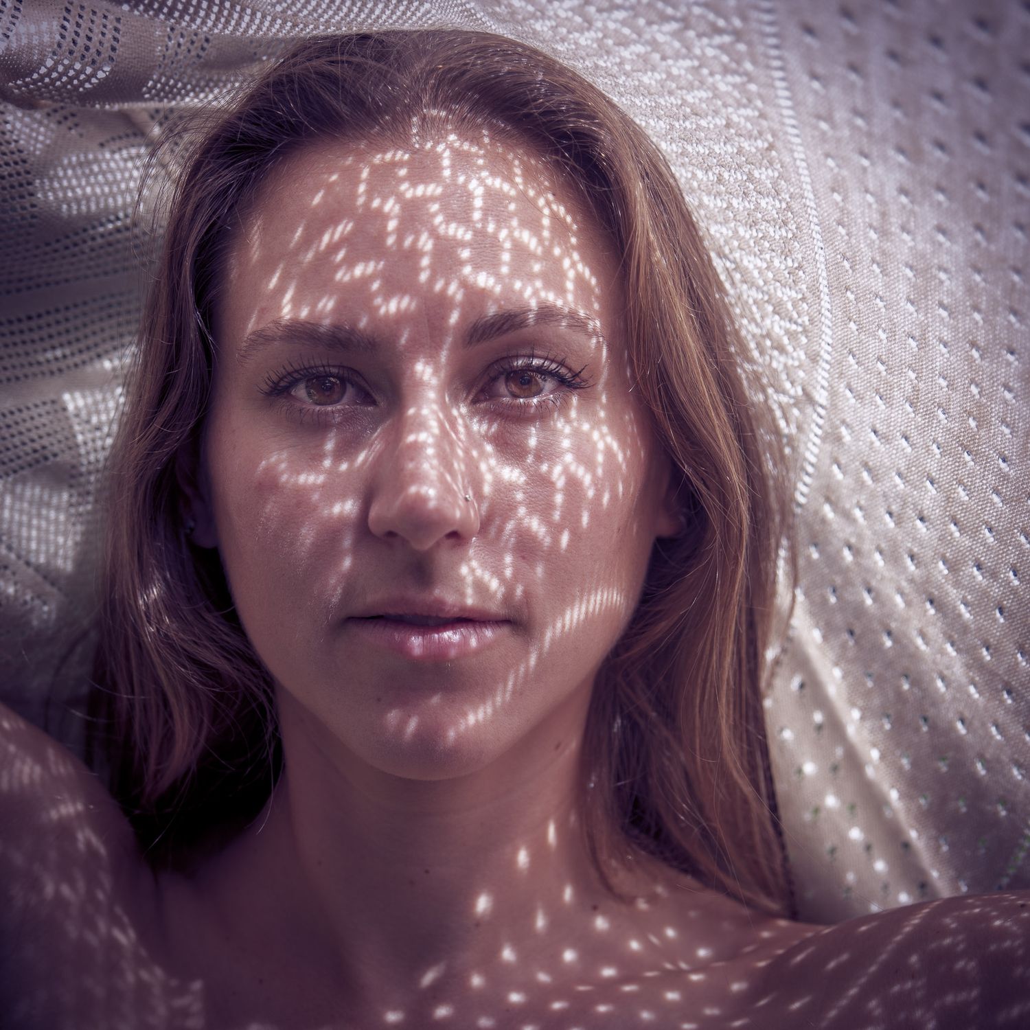Artistic portraits with dappled light patterns creating ethereal shadow effects.