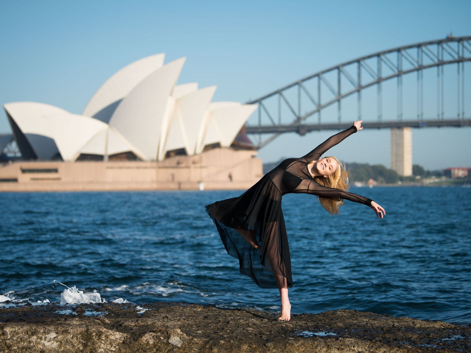 Dancer performs elegant moves with Sydney Harbour Bridge and Opera House in background.