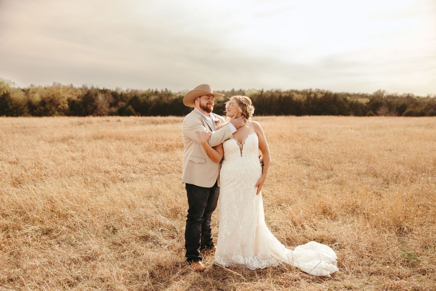 Bride and groom share a tender embrace in a golden autumn field during their outdoor wedding.