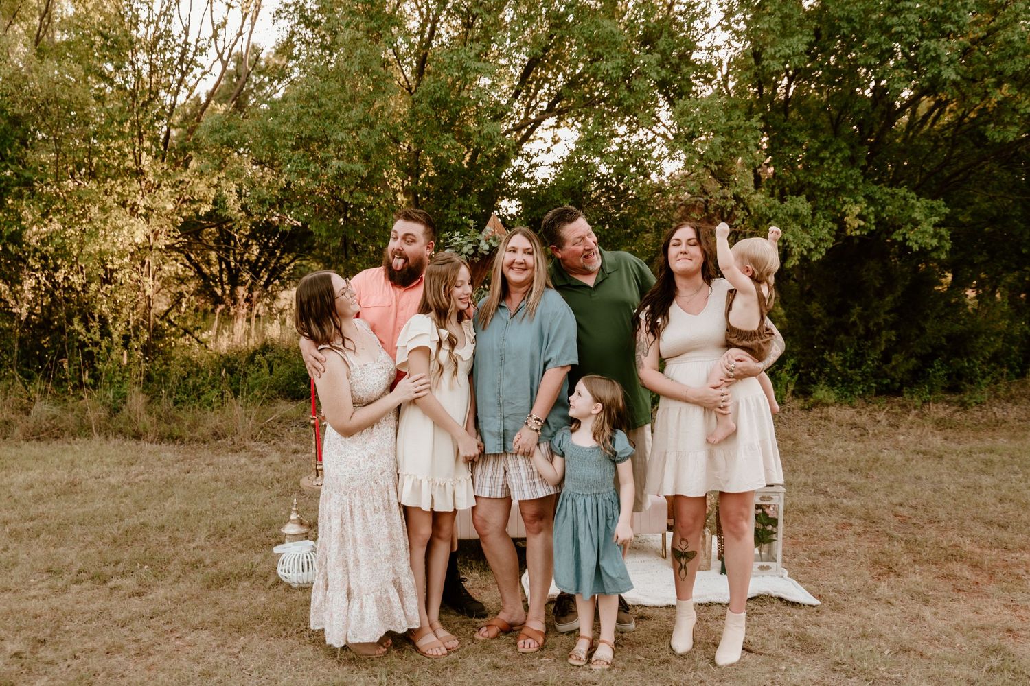 Large family of seven smiles together outdoors during golden hour family portrait session.