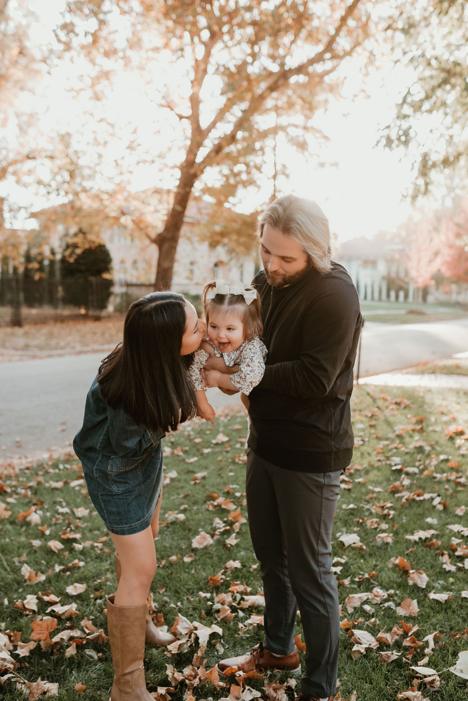 Young couple with baby girl enjoy tender family moment in autumn park setting.