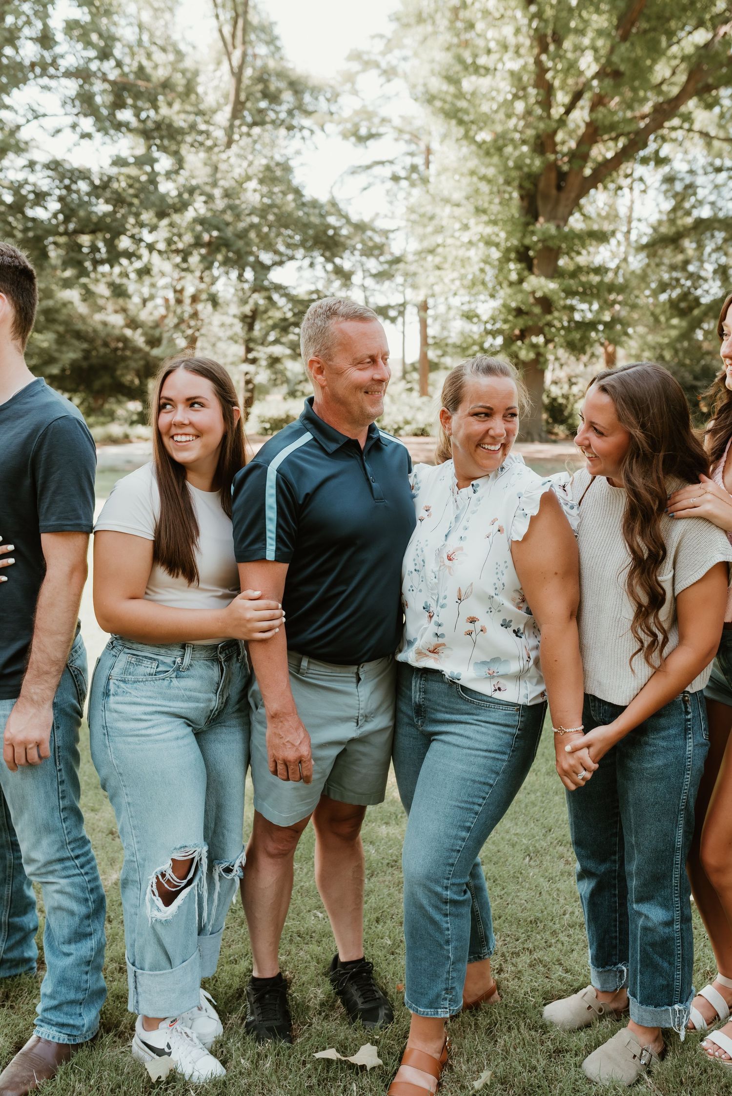 Happy family laughing and embracing outdoors in a lush green park during summer.