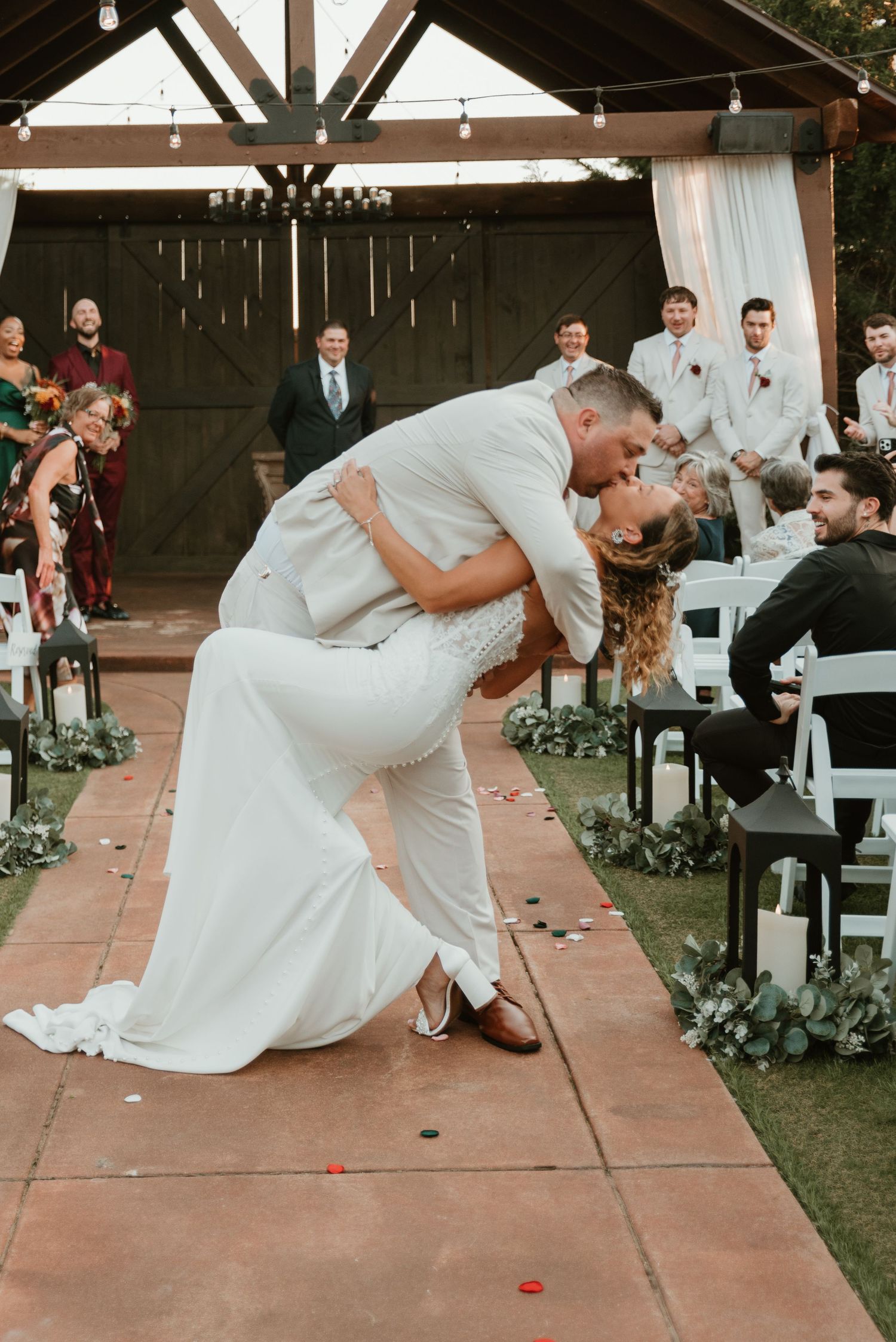 Groom dipping bride for a romantic kiss at the end of their outdoor wedding ceremony.