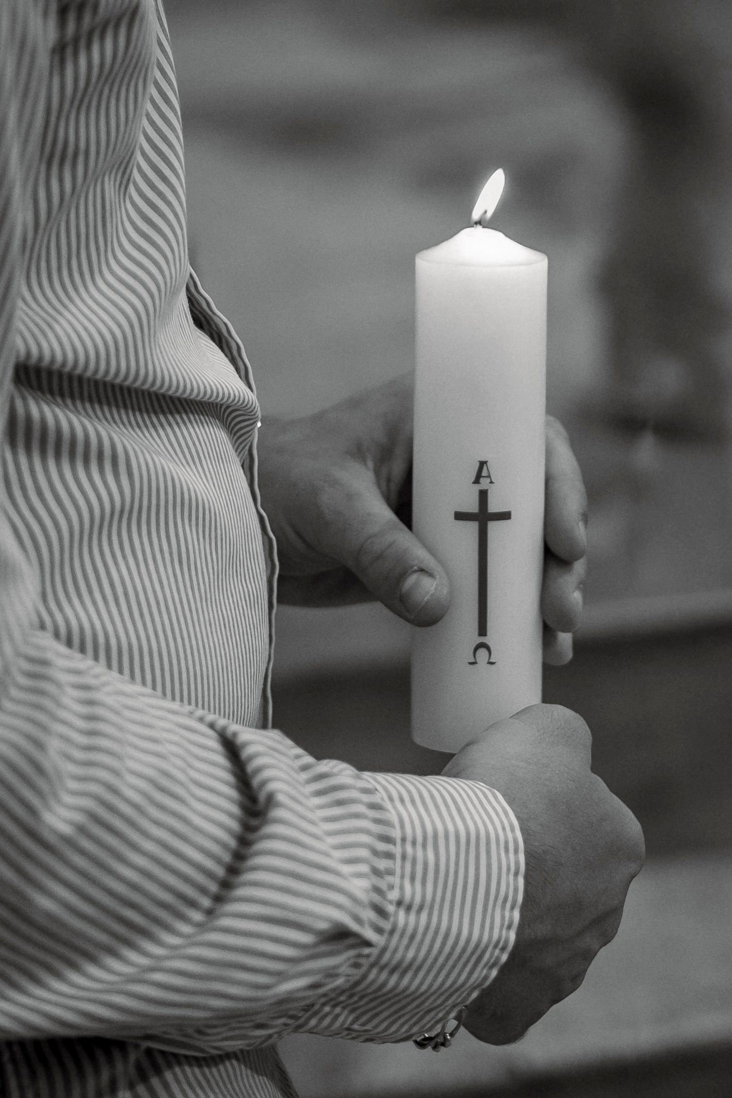 photo en noir et blanc d'un cierge de baptême tenu entre les mains
