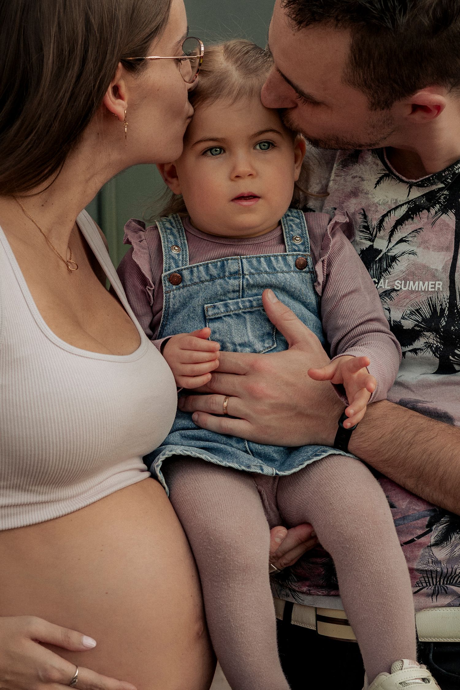 photo de grossesse en famille avec les parents embrassant leur fille