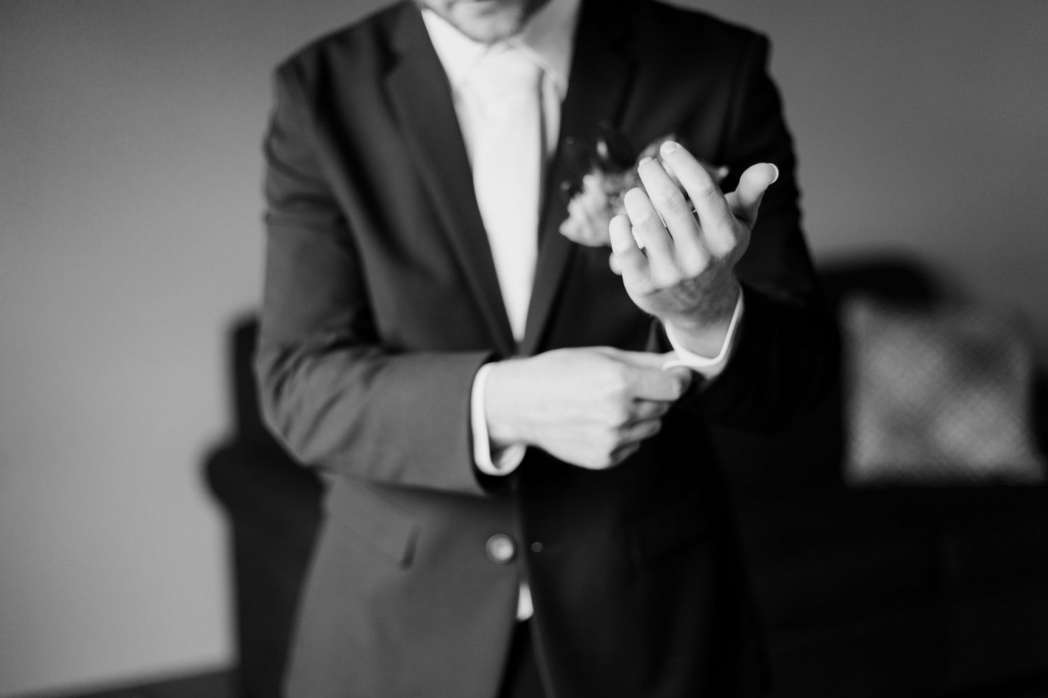 A person in formal attire claps their hands while wearing a dark suit and tie.