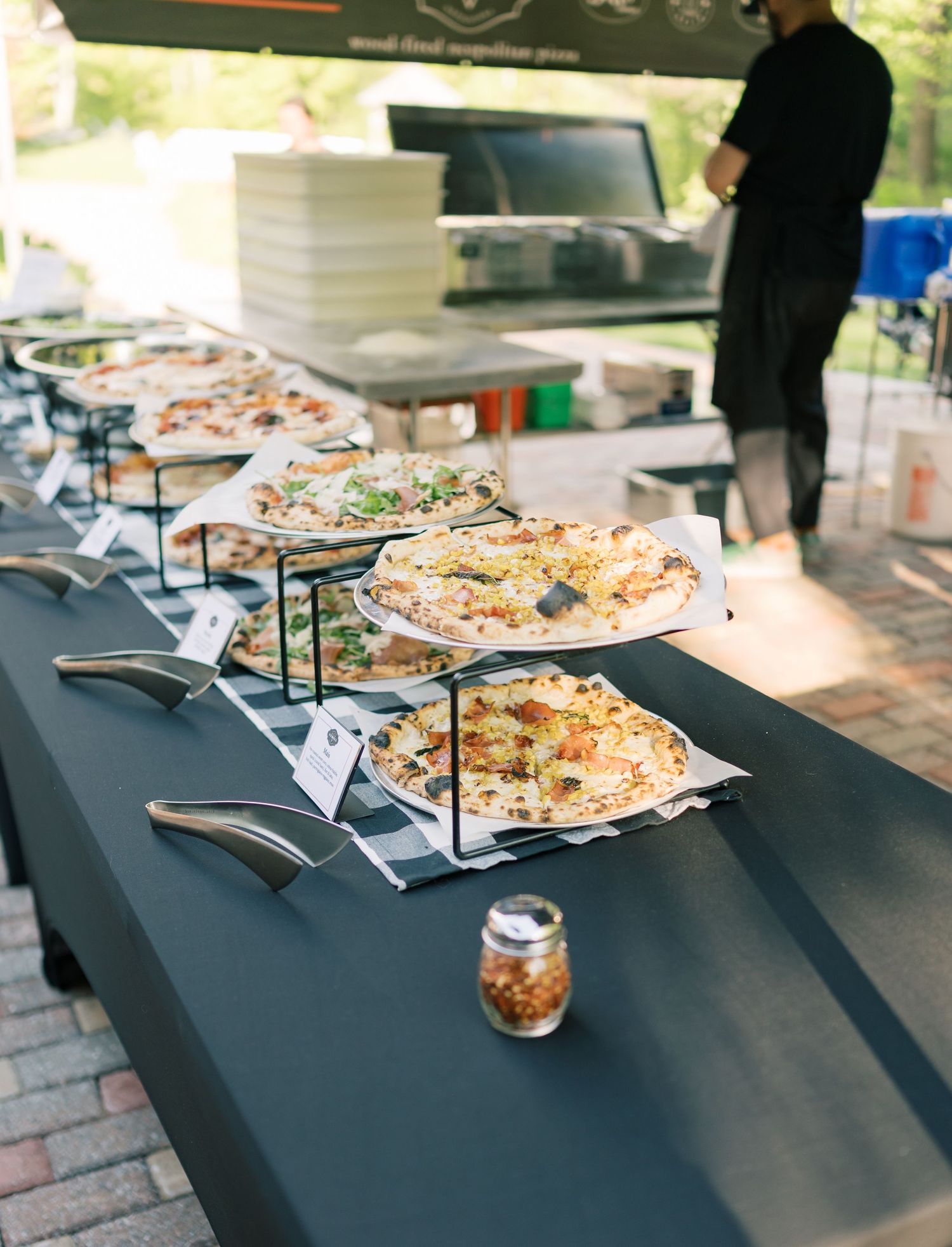 A catering buffet display features platters of food arranged on black tables with serving utensils.