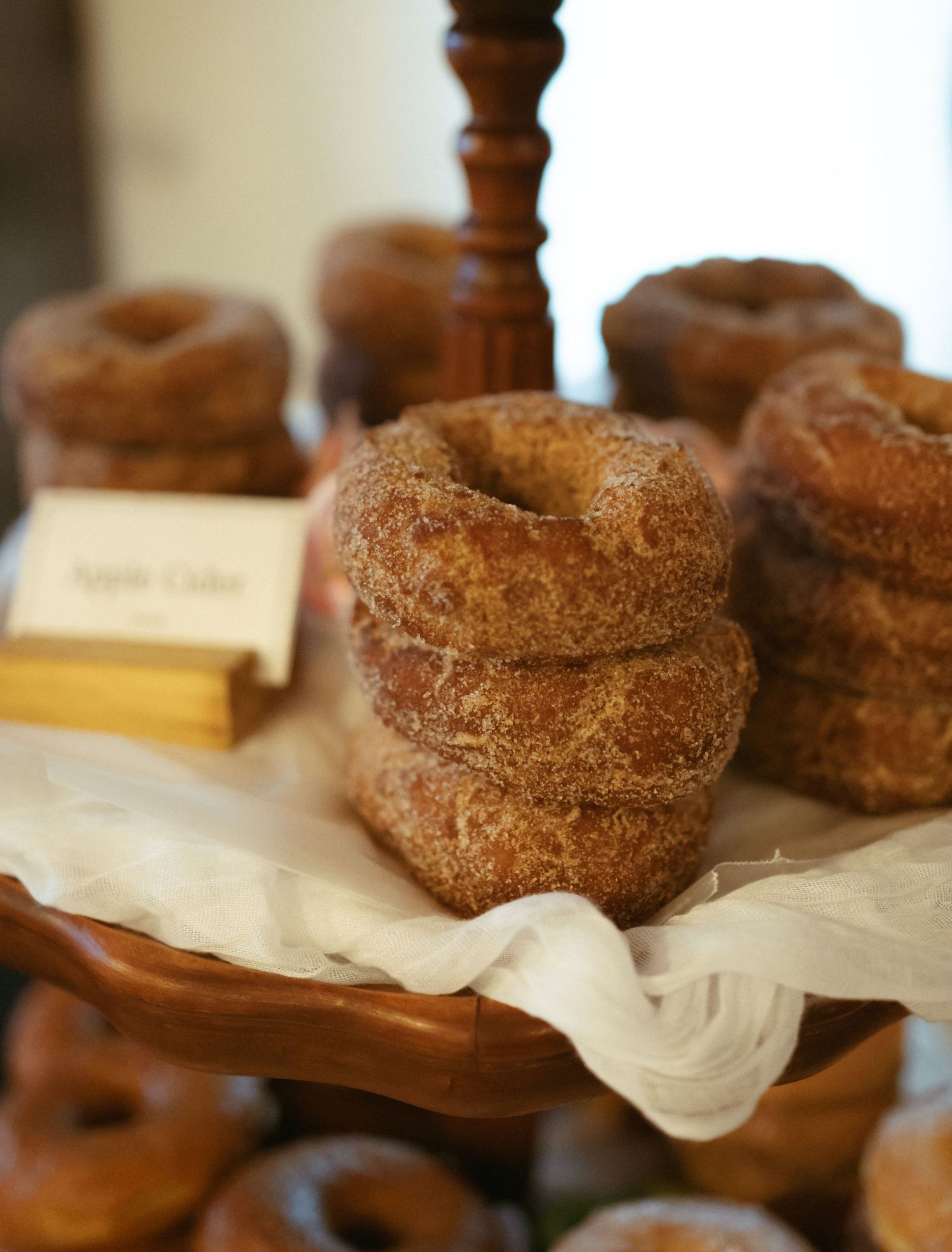 Stack of freshly baked cinnamon sugar donuts on parchment paper with wooden decor in background.