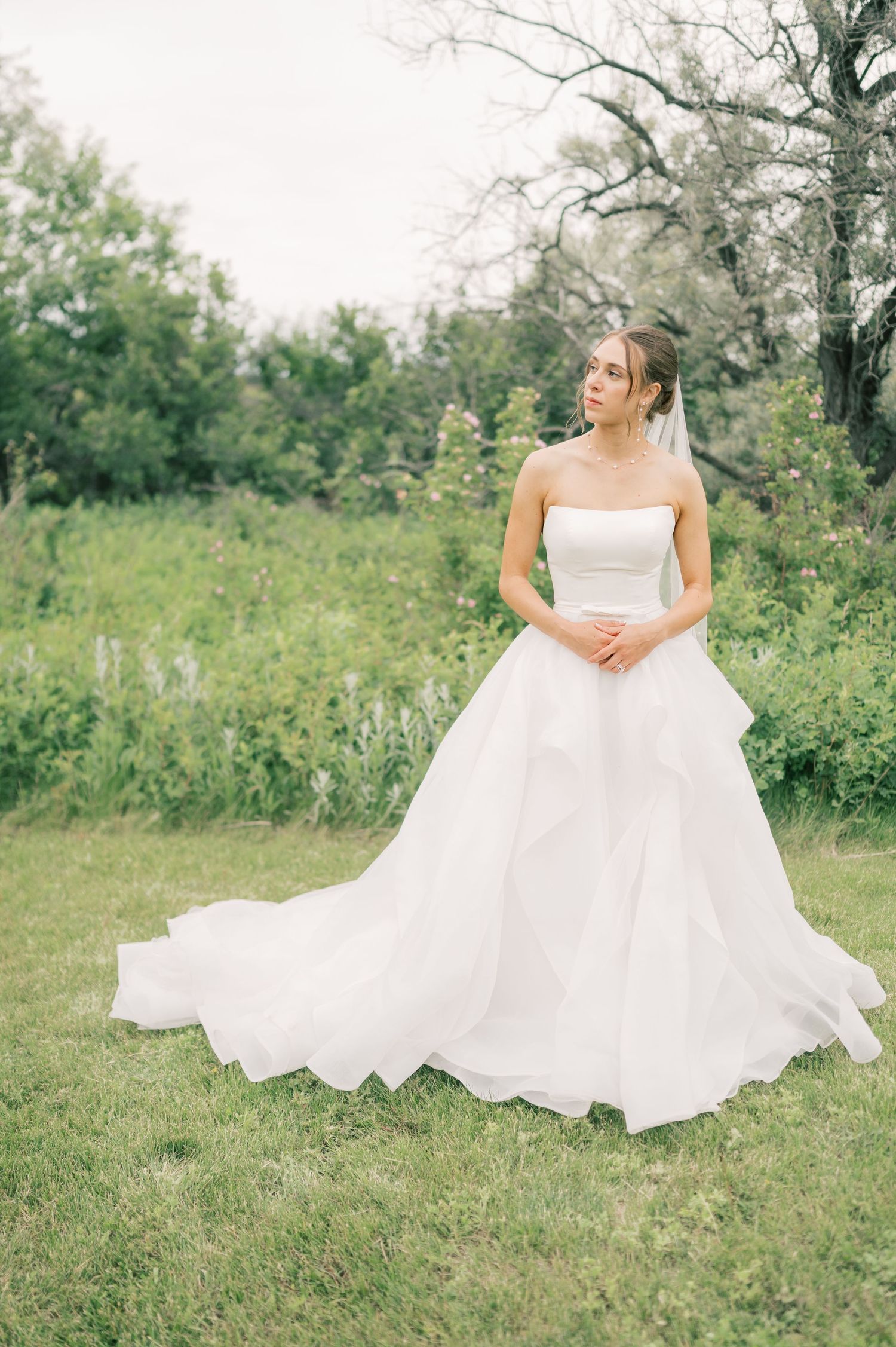 A flowing white wedding dress twirls gracefully in a series of romantic outdoor portraits set against lush green foliage.