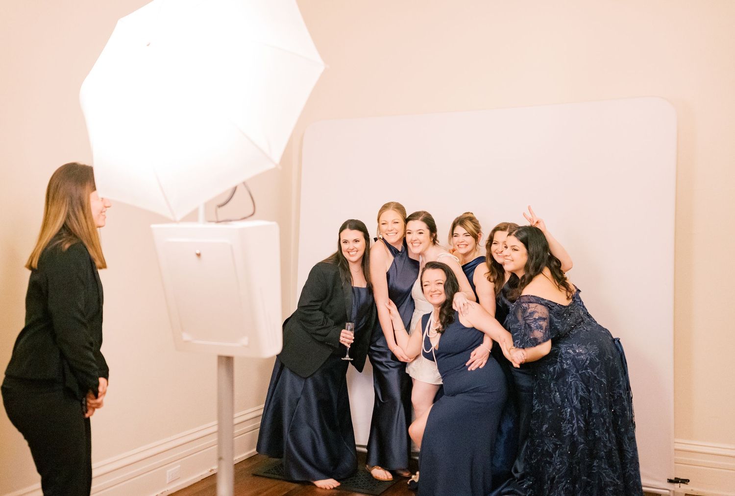 A group of people in formal attire gathered in a bright hallway for a social event.