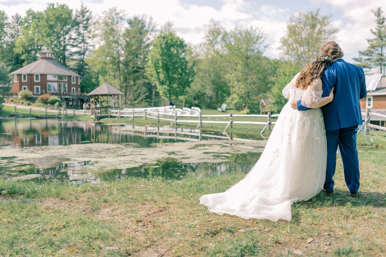 A couple in wedding attire walks together on a rustic wooden bridge surrounded by autumn foliage.
