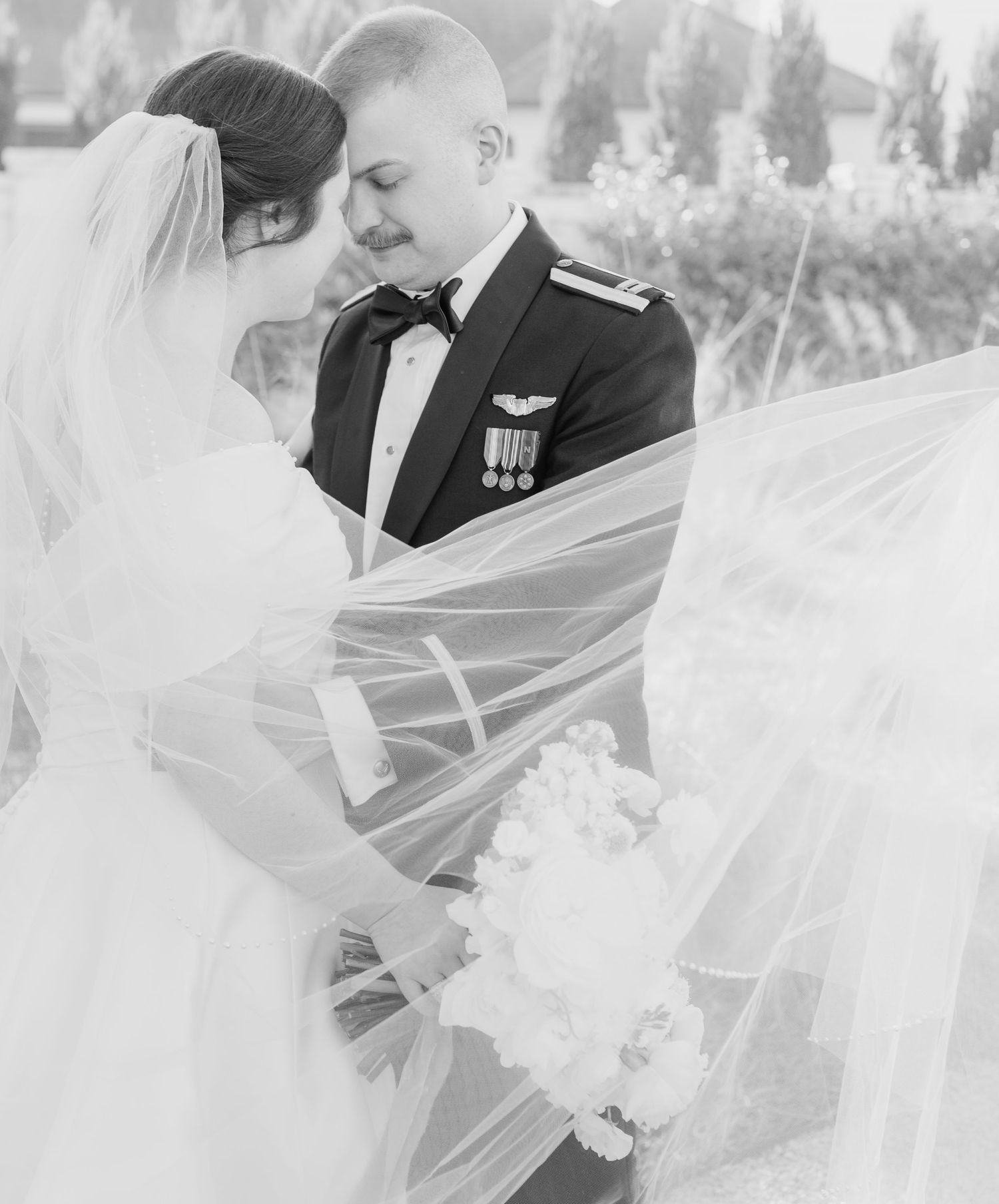 A romantic black and white wedding photo series showing intimate moments between a couple through their veil.