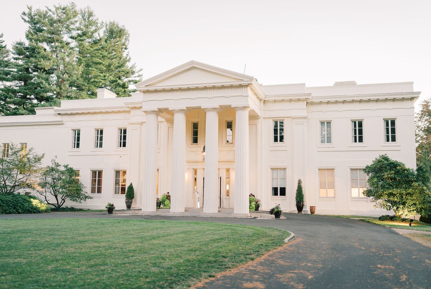 A panoramic view of a white neoclassical building with columns and manicured lawn in the foreground. Wadsworth Mansion in Middletown, CT