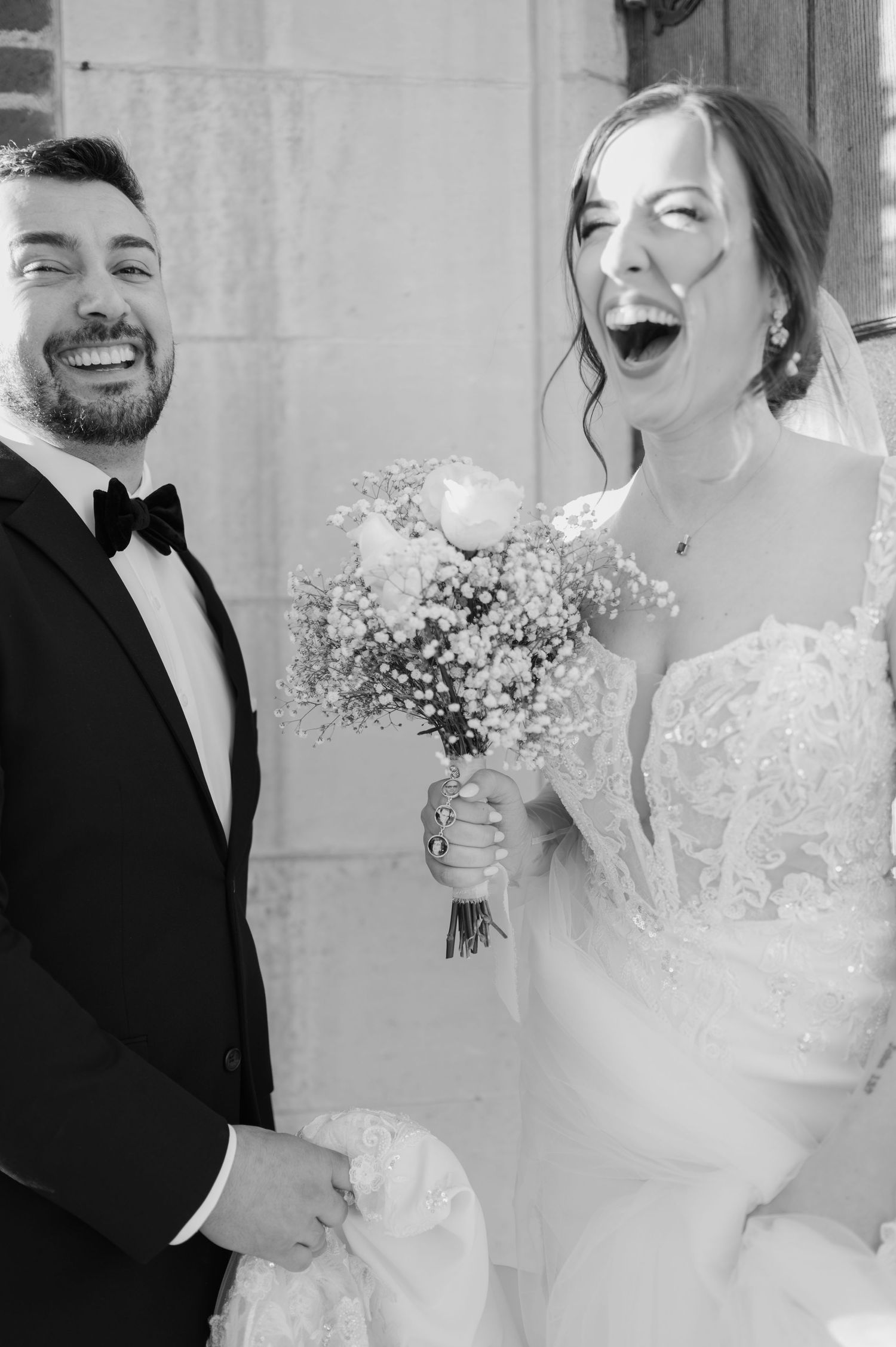 Black and white photo series of joyful wedding couple laughing together while holding a delicate bouquet of baby's breath.