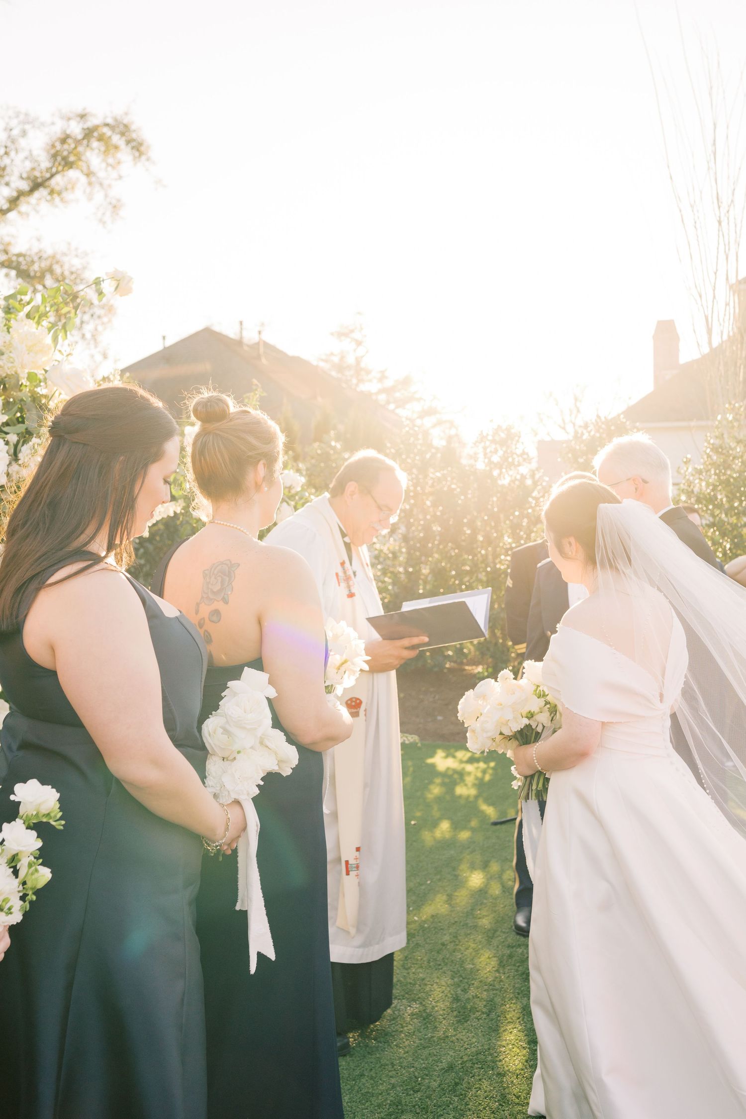 Wedding party stands in a line during golden hour sunlight creating a dreamy backlit silhouette effect.