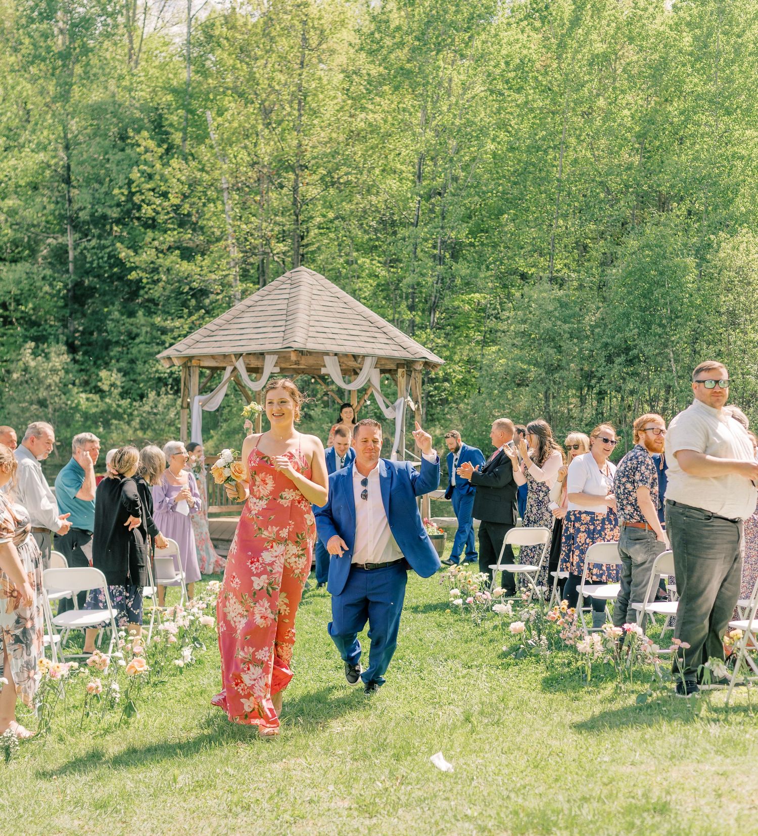 Wedding guests participate in a fun outdoor group activity on a sunny day in a lush green garden setting.