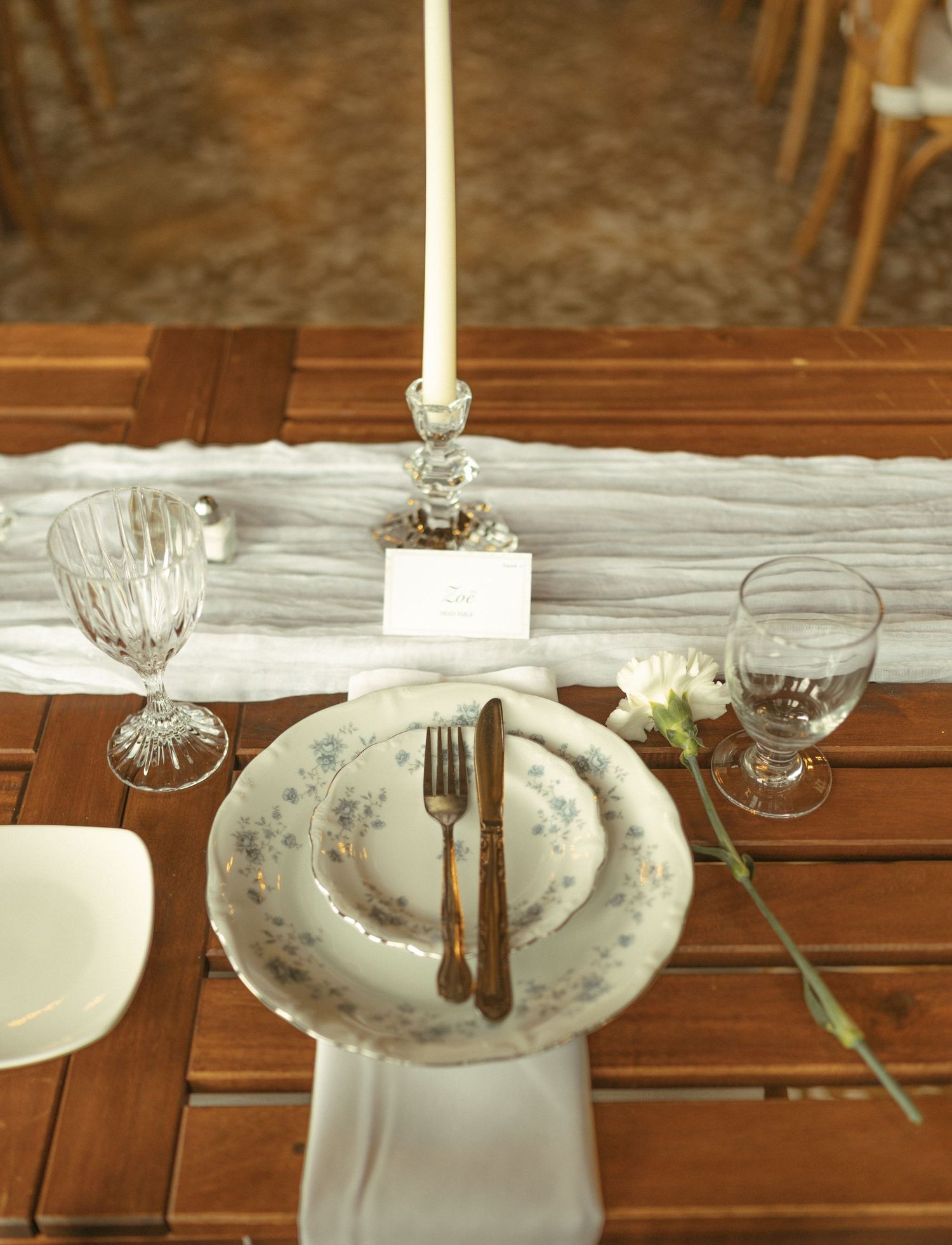 A formal dining table setting with crystal glasses and white plates on a wooden surface.