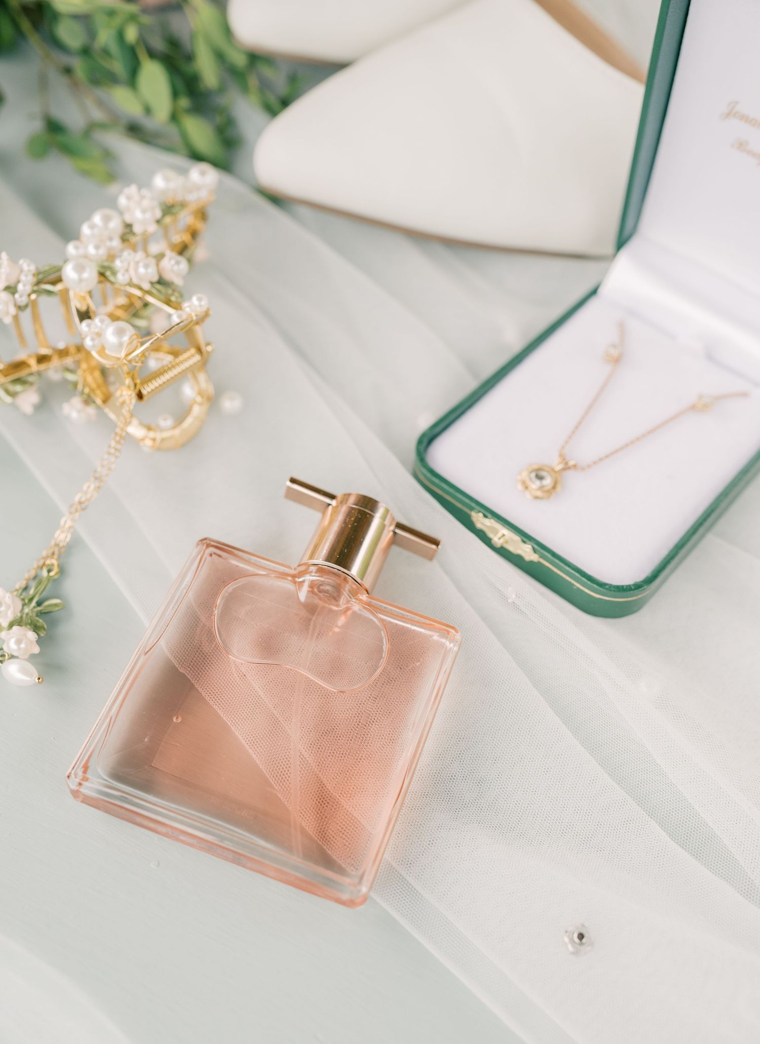 Elegant perfume bottle collection in soft pink and gold tones displayed on white marble surface with delicate floral accents.