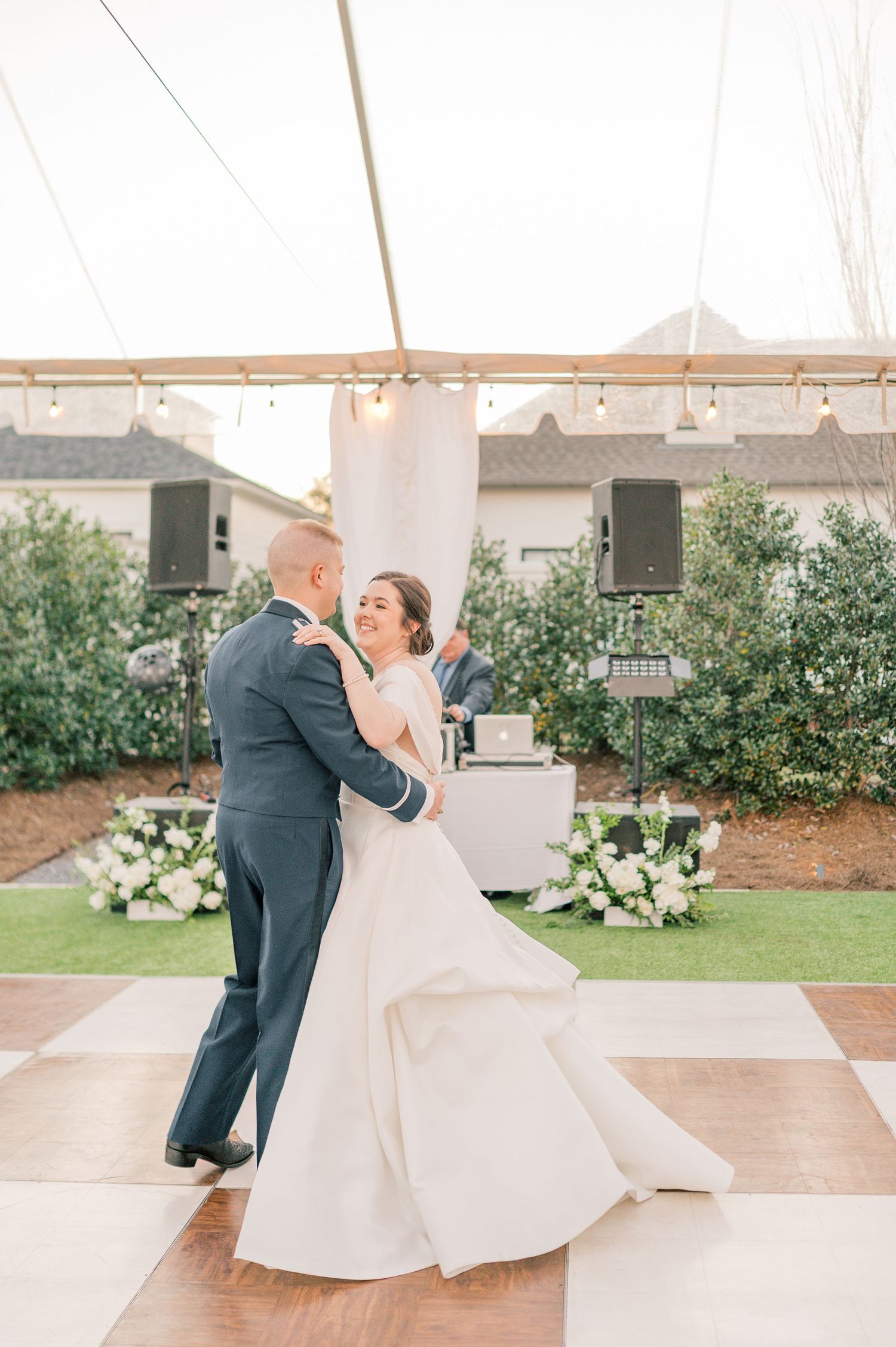 A couple shares an elegant dance during their wedding reception on an outdoor patio.