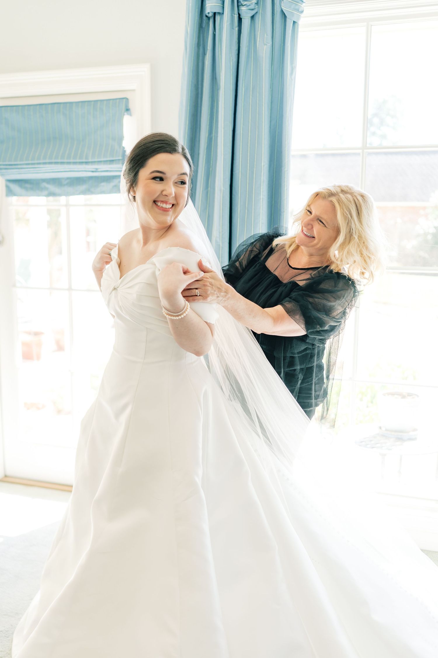 A person in a white dress twirls gracefully in a sunlit room with blue curtains in the background.