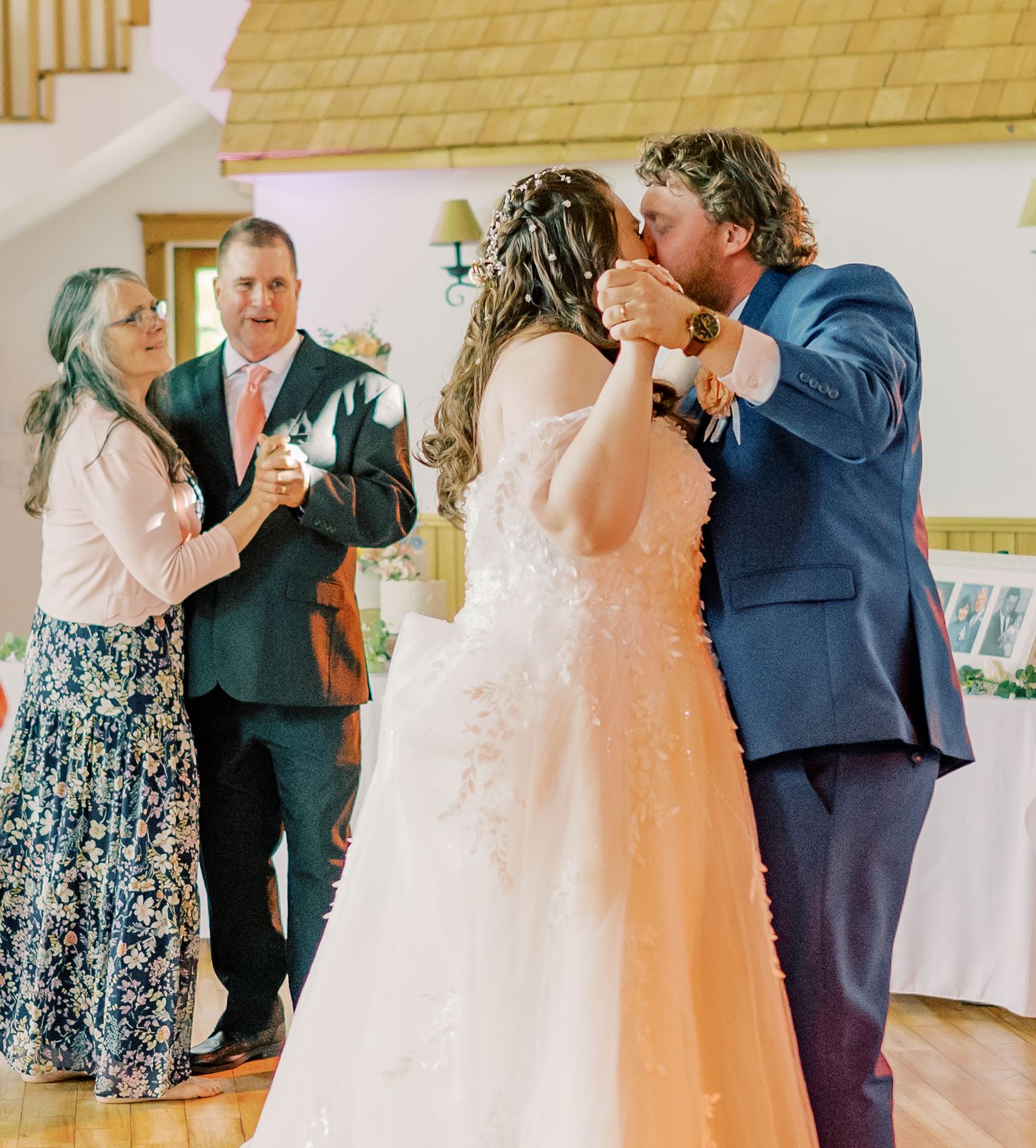 Wedding reception celebration with guests dancing and socializing in an indoor venue with warm lighting.