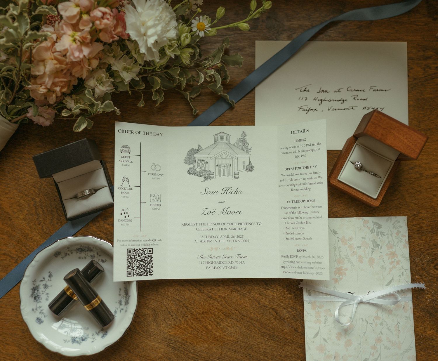 Wedding invitation suite with floral arrangements, marble plates, and QR codes displayed on a rustic wooden table.