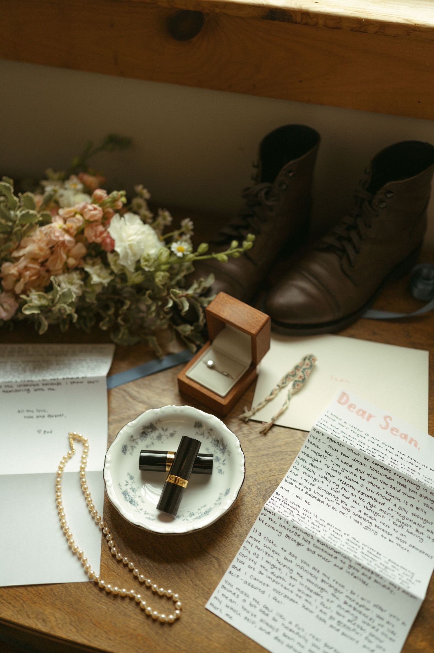 A series of handwritten letters with pearls, flowers, and a perfume bottle arranged in a vintage style flatlay composition.