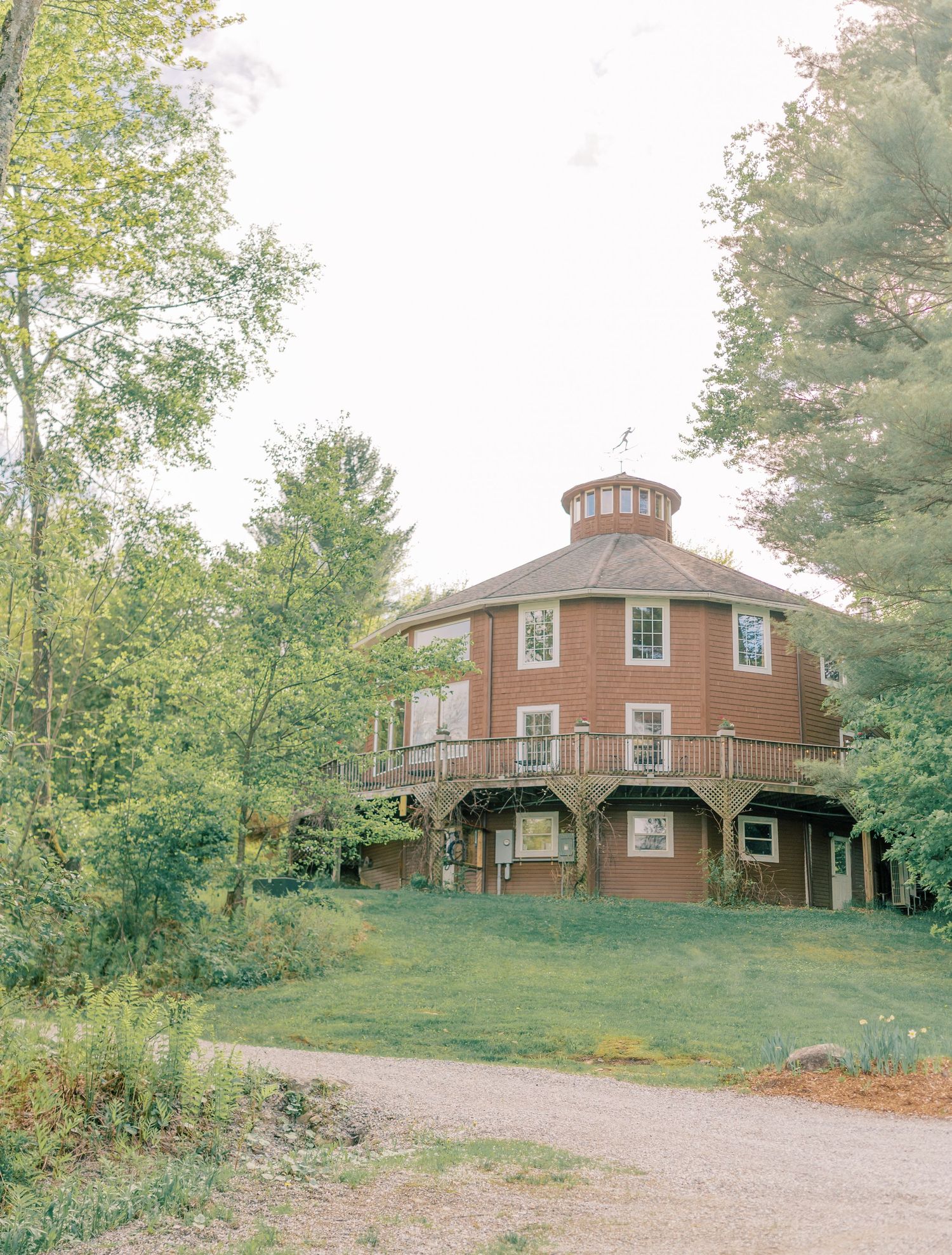 A panoramic view of three rustic wooden cabins nestled on a grassy hillside surrounded by trees.