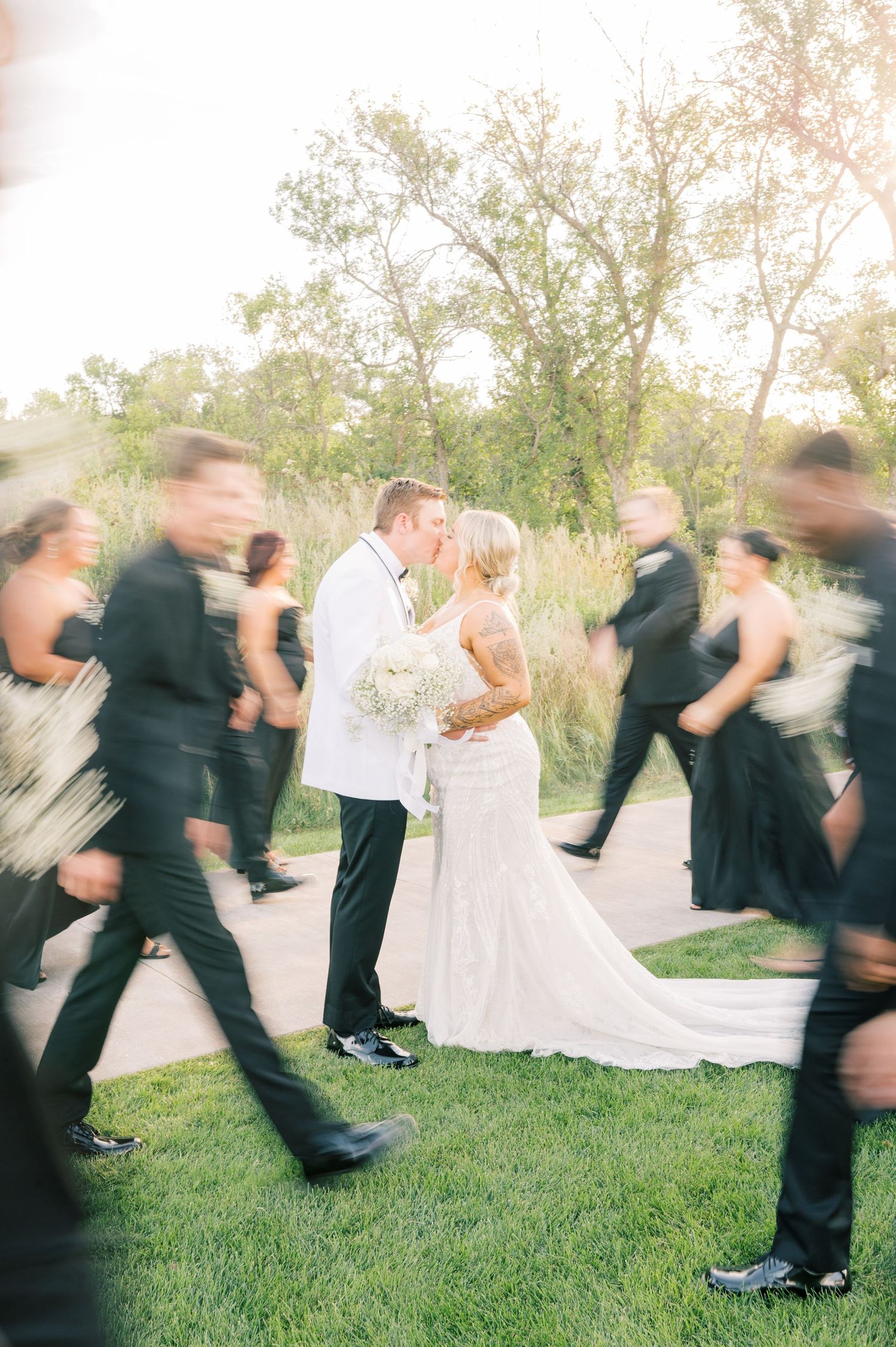 Motion blur captures wedding party members running and jumping on grass in a fun action sequence.