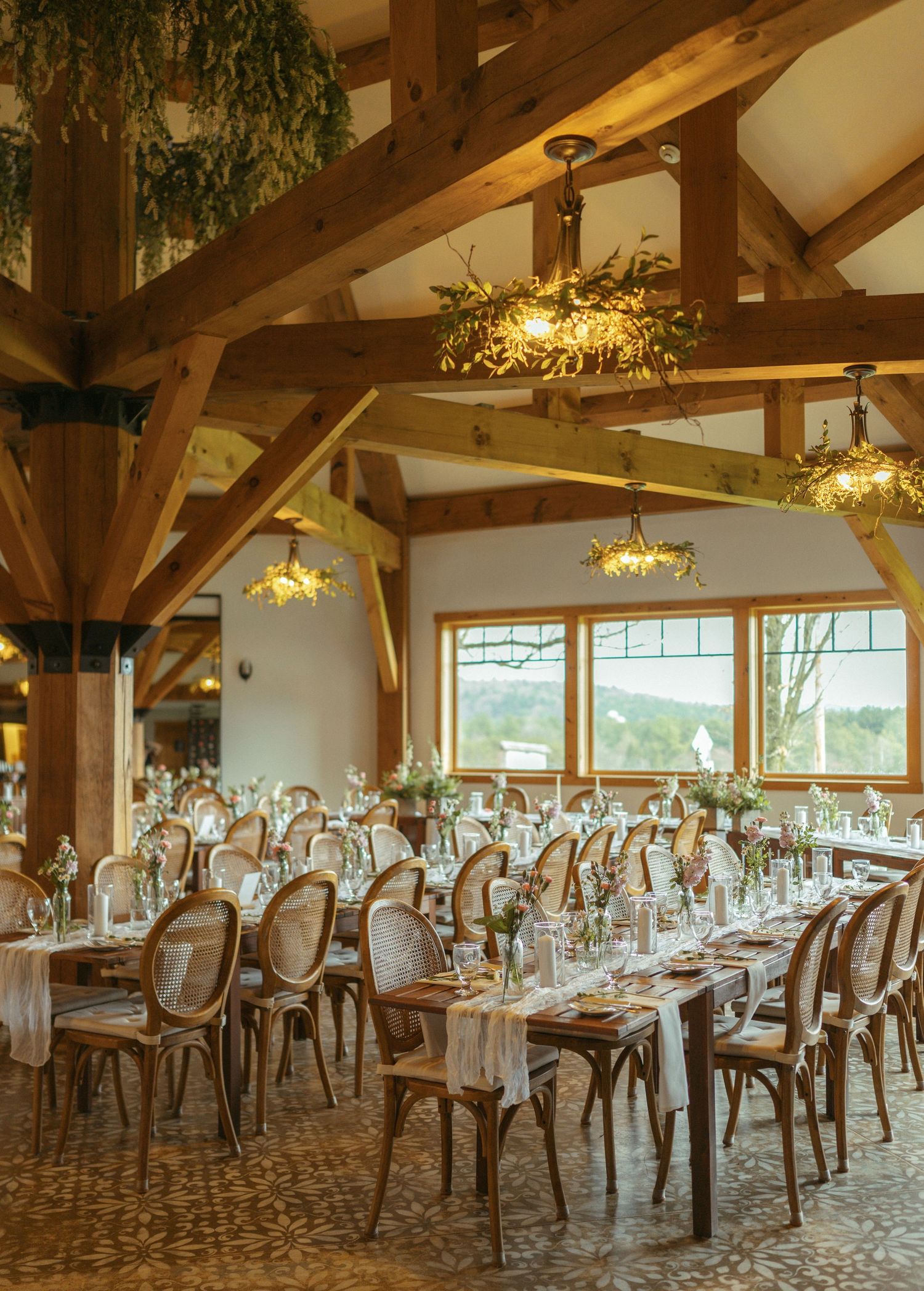 Elegant banquet hall with exposed wooden beams, crystal chandeliers, and formal table settings for an upscale event.