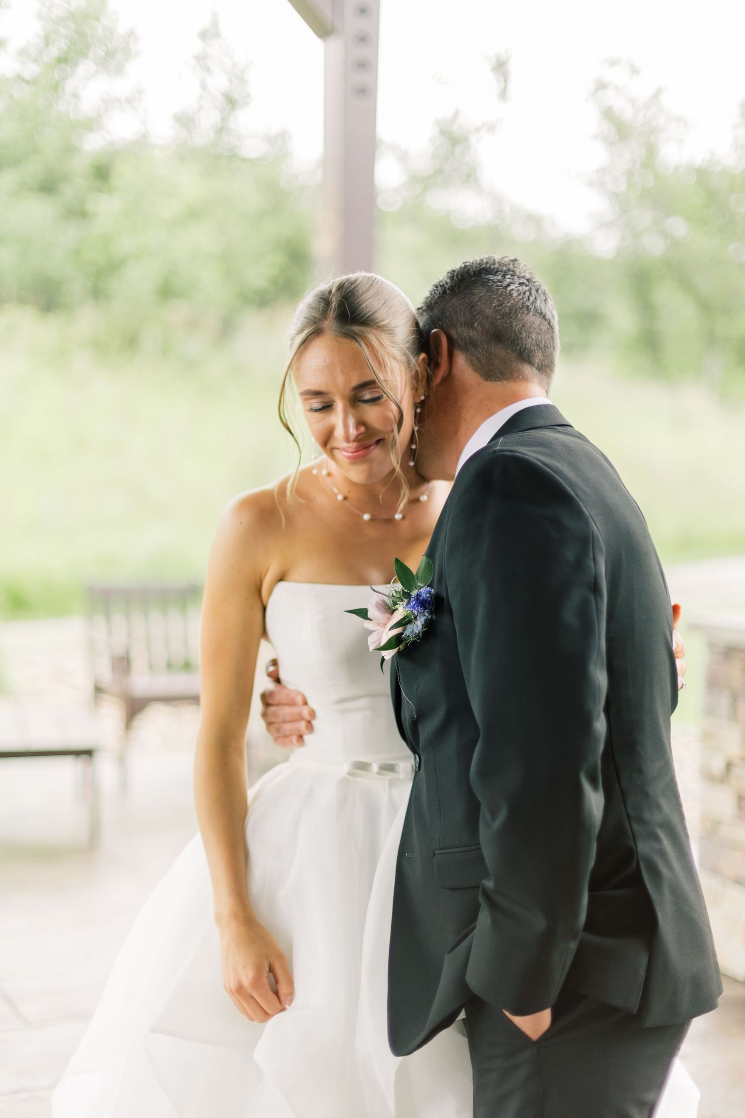 A tender moment between a couple on their wedding day, with the bride in white and groom in dark suit.