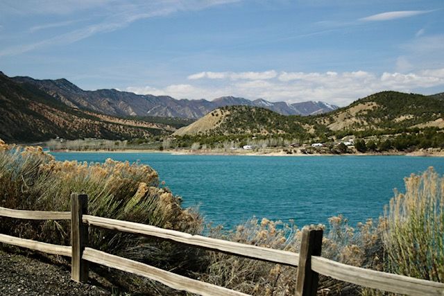 Turquoise lake waters surrounded by mountain peaks and wooden boardwalk in a scenic landscape.
