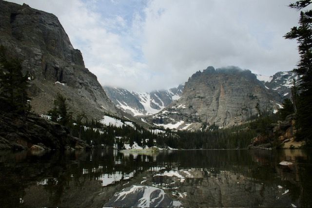 Dramatic mountain panorama featuring steep rocky cliffs and alpine lakes in a rugged wilderness setting.