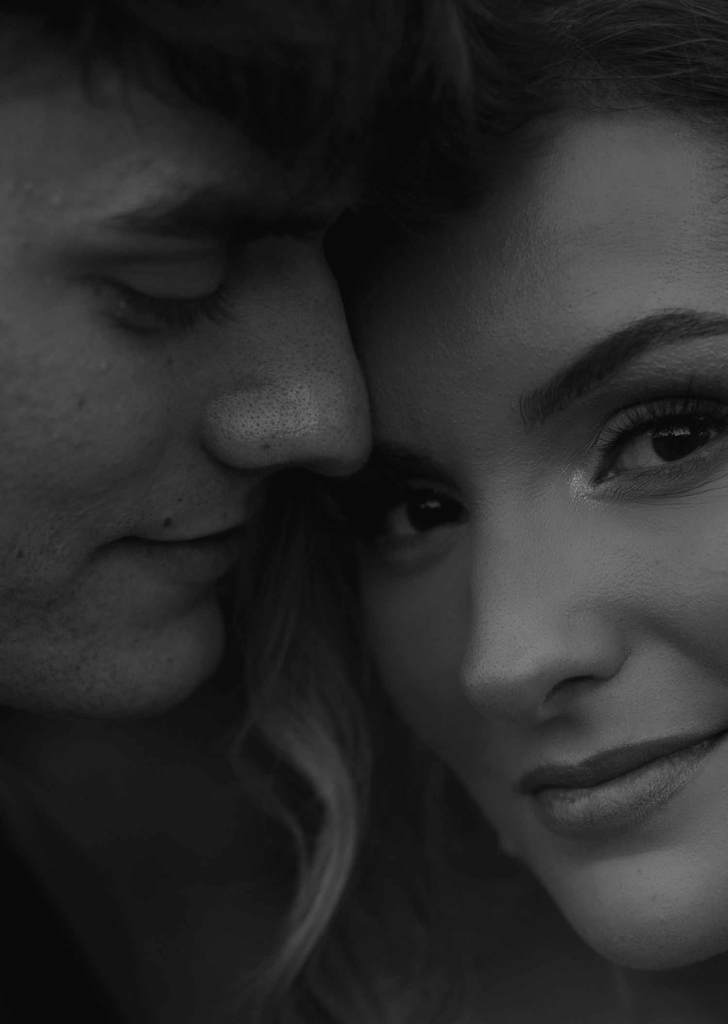 Intimate black and white close-up portrait of a couple sharing a tender romantic moment.