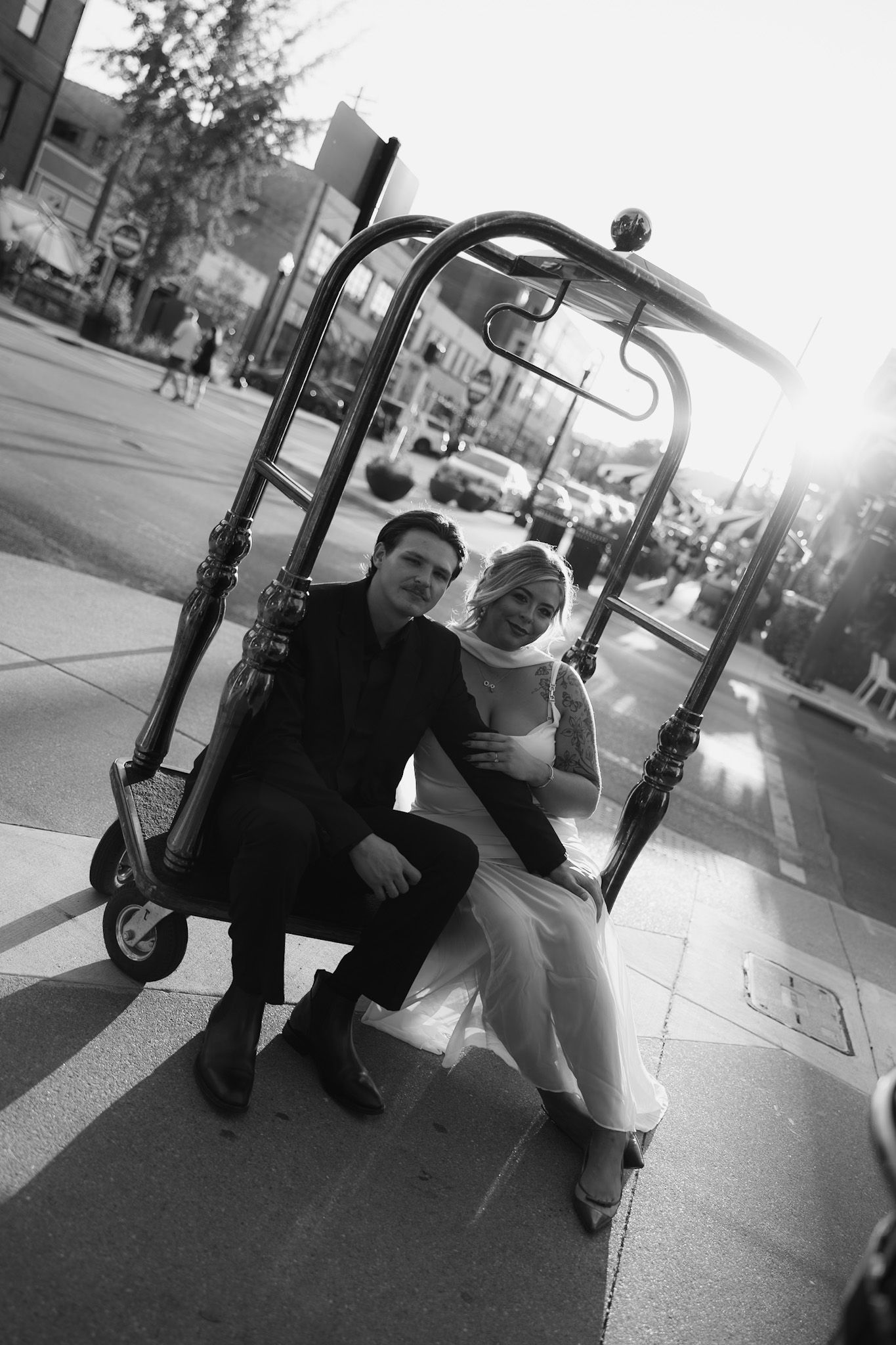 A couple sits together on a bench at night in black and white.