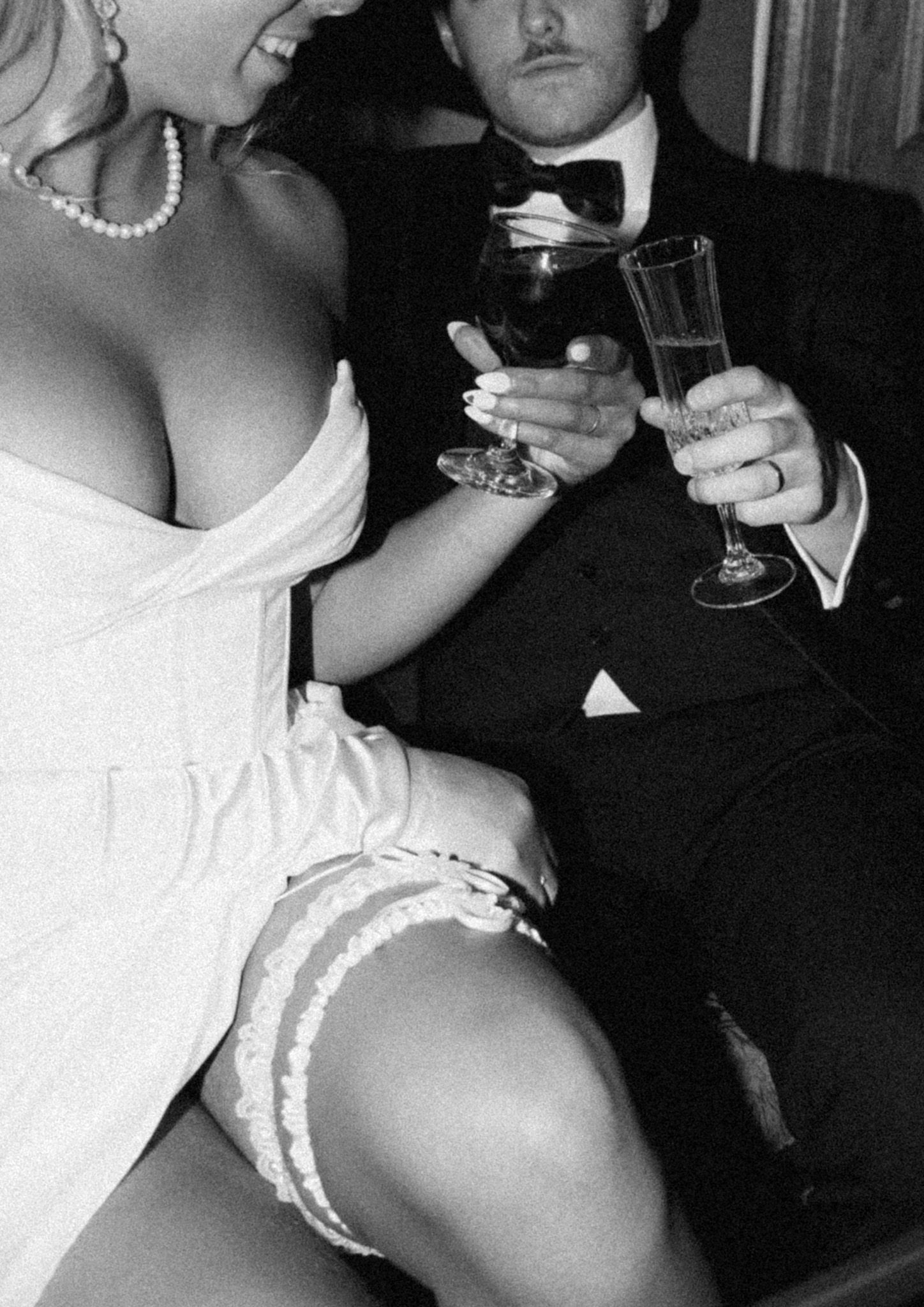 Couple in formal attire sharing champagne at an elegant wedding reception.