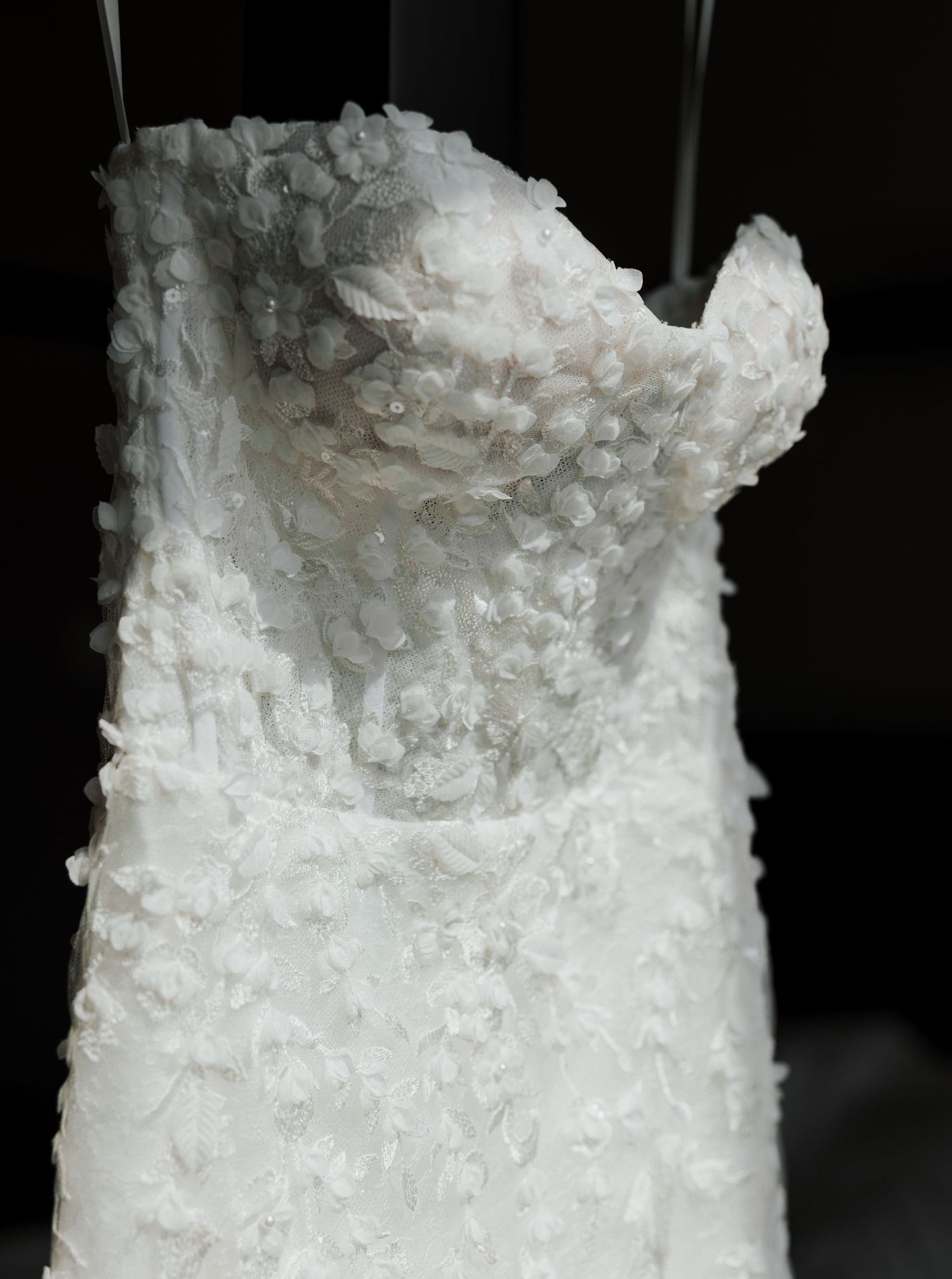 Detail shot of white textured wedding dress bodice with delicate beading pattern.