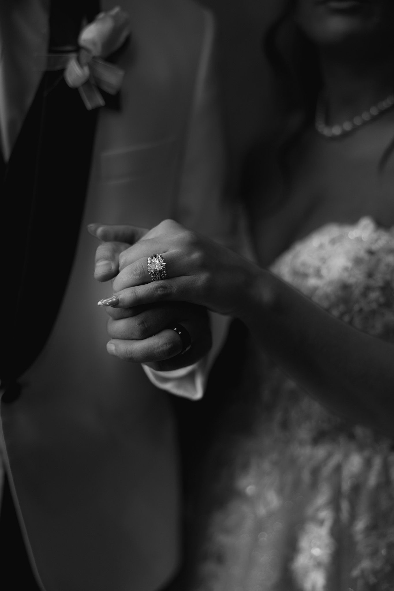 Close-up details of wedding jewelry and lace dress elements in black and white photography.