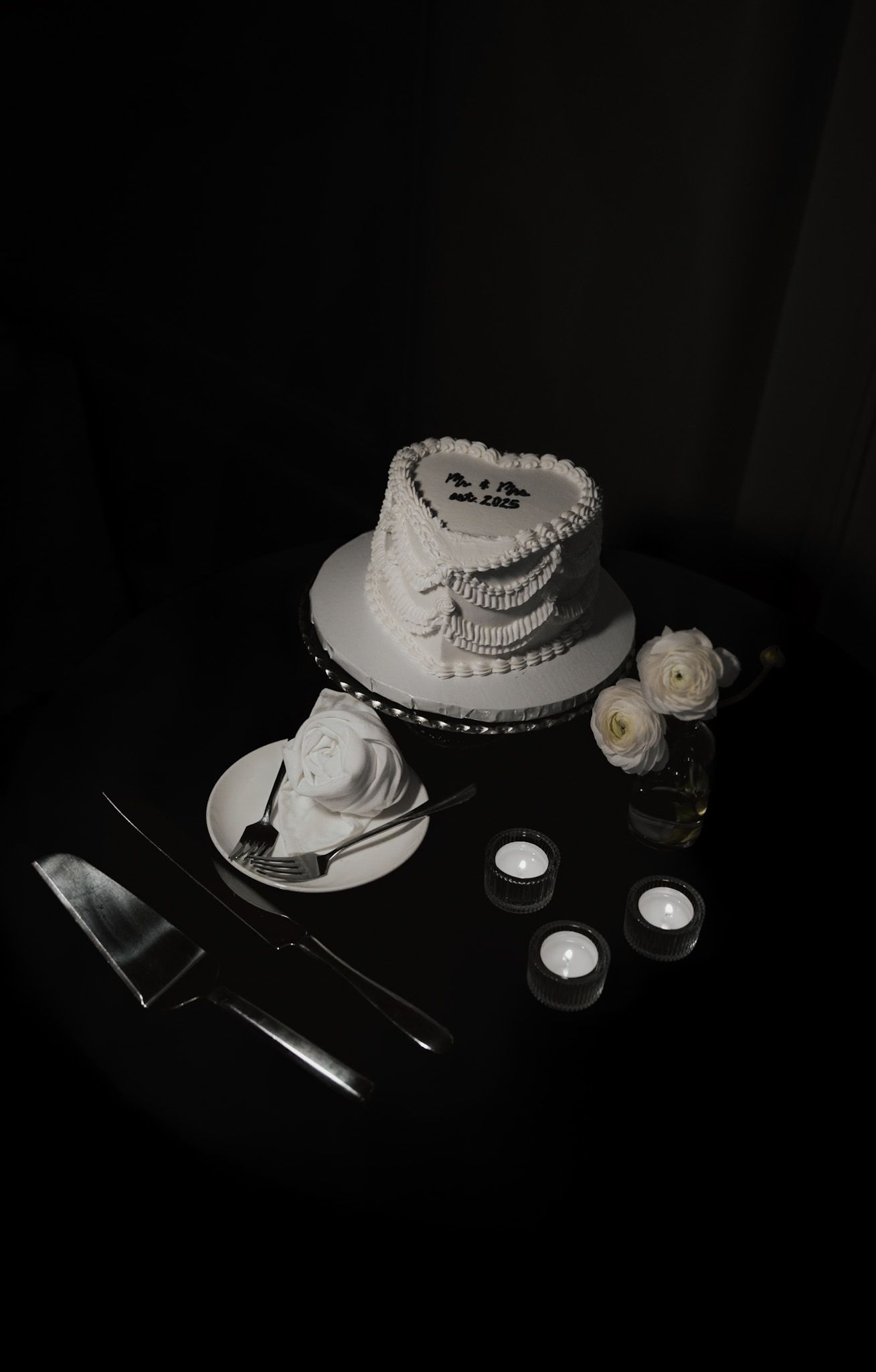 Moody still life of a white cake and candles in dark atmospheric lighting.